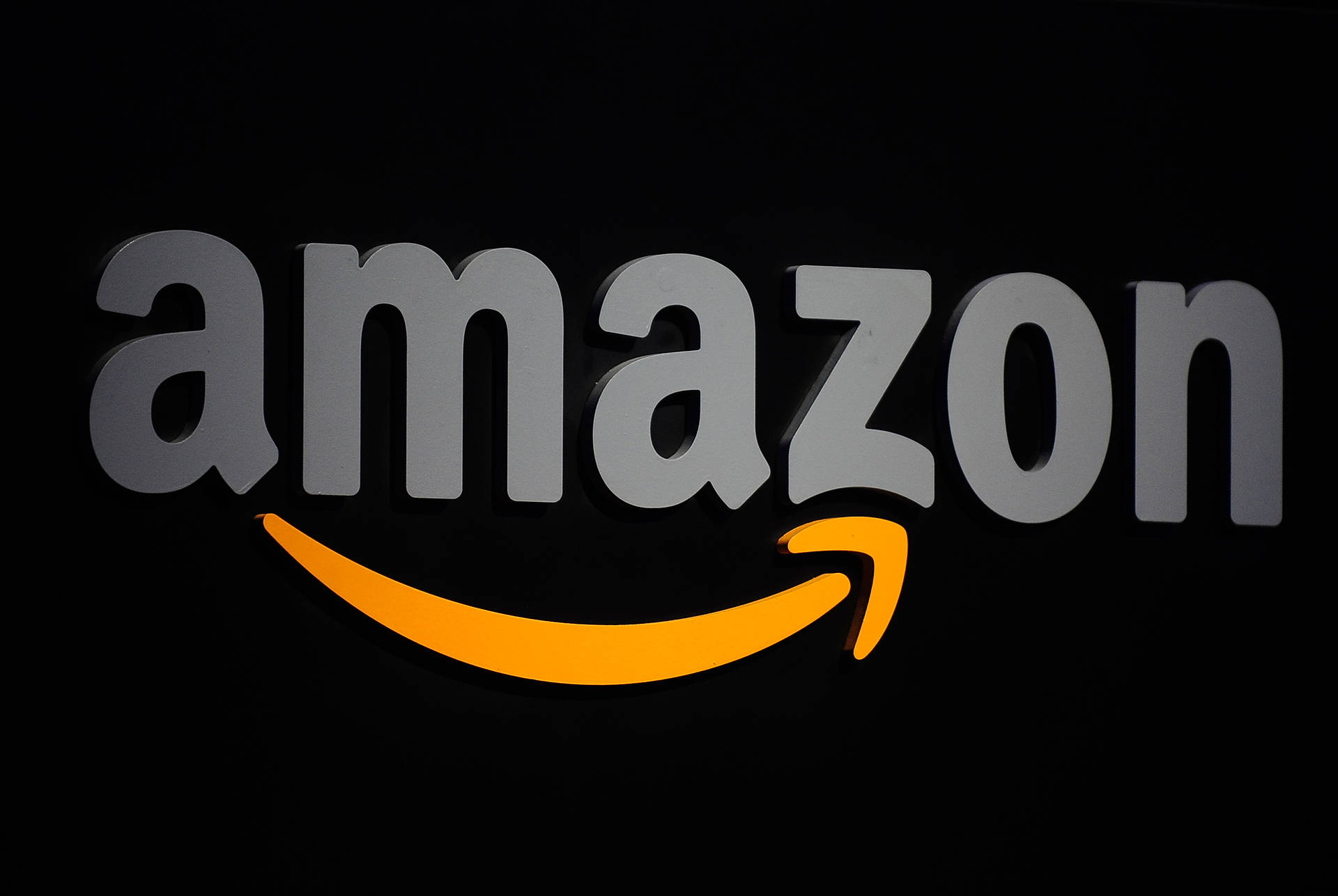 黑色背景上帶有灰色字母和橙色箭頭的Amazon標誌。