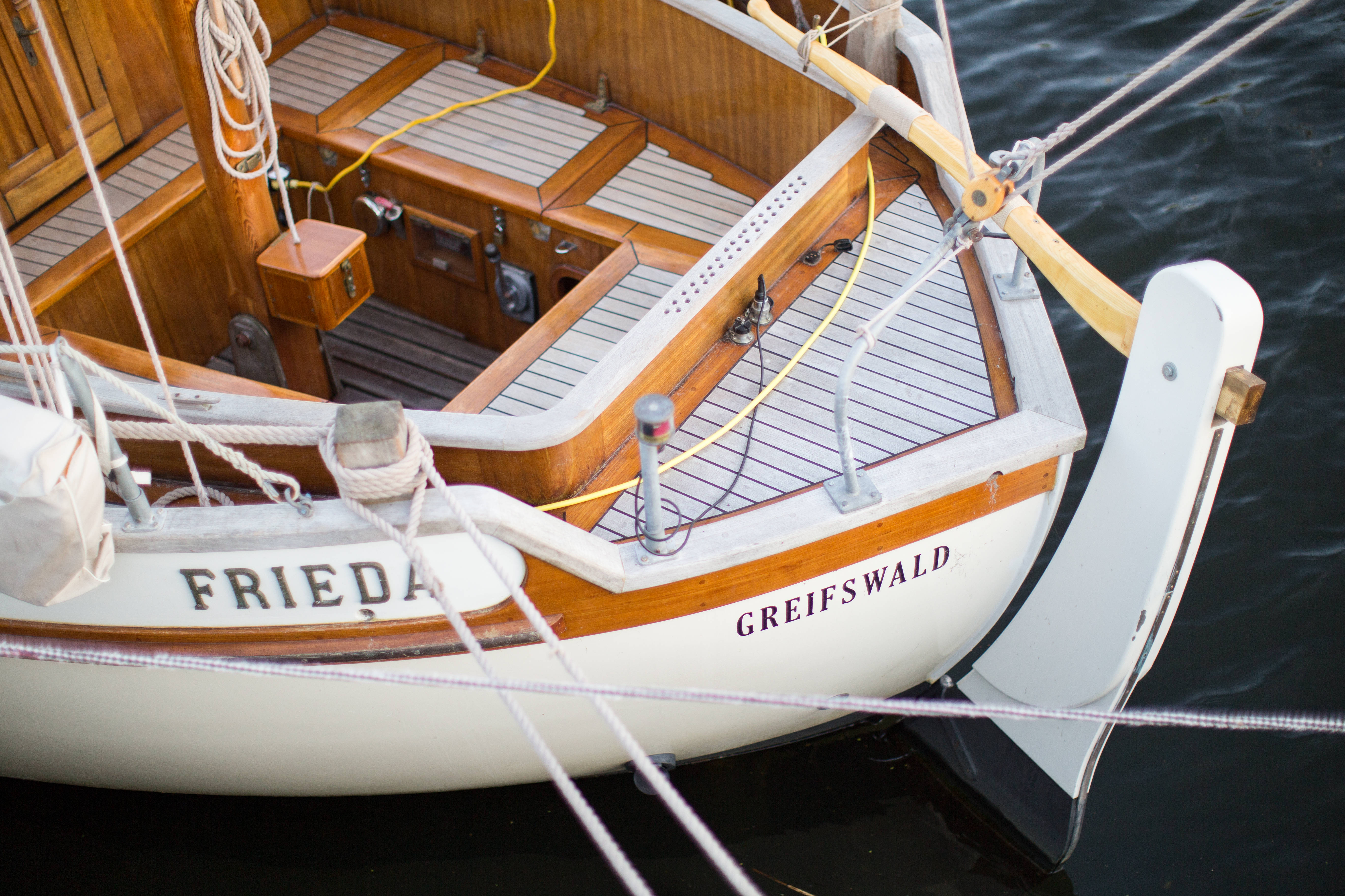 黑水上的豪華遊艇 壁紙 — 經典木製帆船名為 'Frieda' 的船身上有 'Greifswald' 字樣，漂浮在平靜的深色水面上，特寫鏡頭。