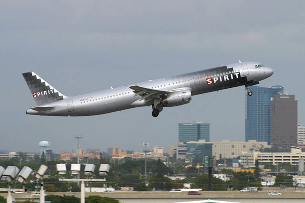 精神航空飛機在城市上空起飛，有建築物和機場燈光。