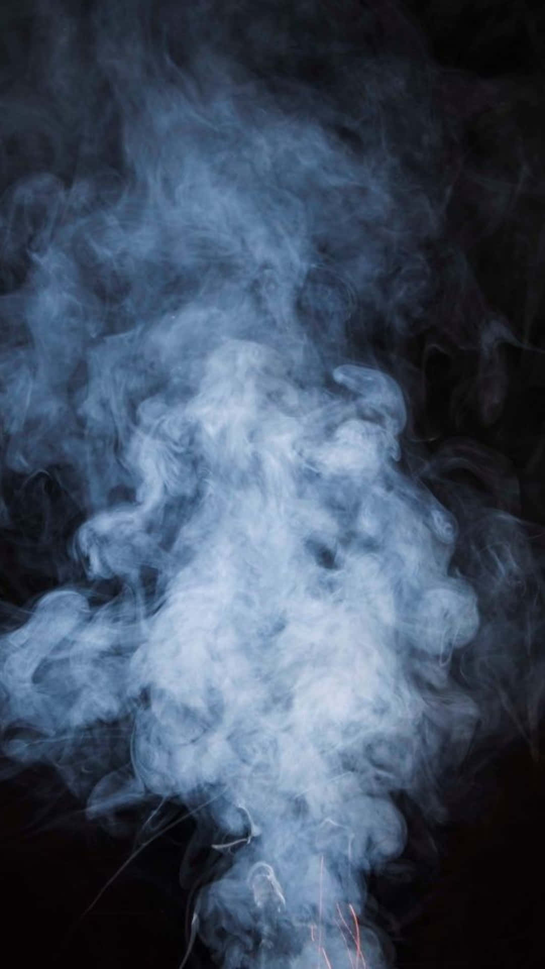黑色背景上旋轉的藍色煙霧與發光餘燼