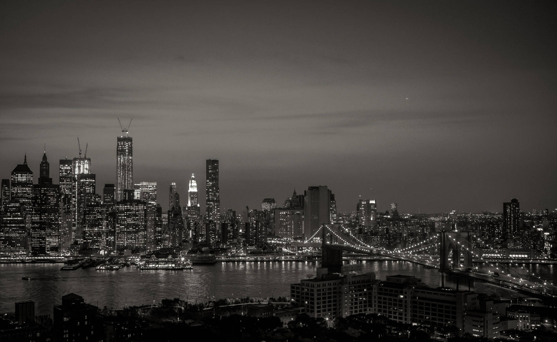 紐約天際線的黑白夜景，有明亮的建築物和水上的橋樑。