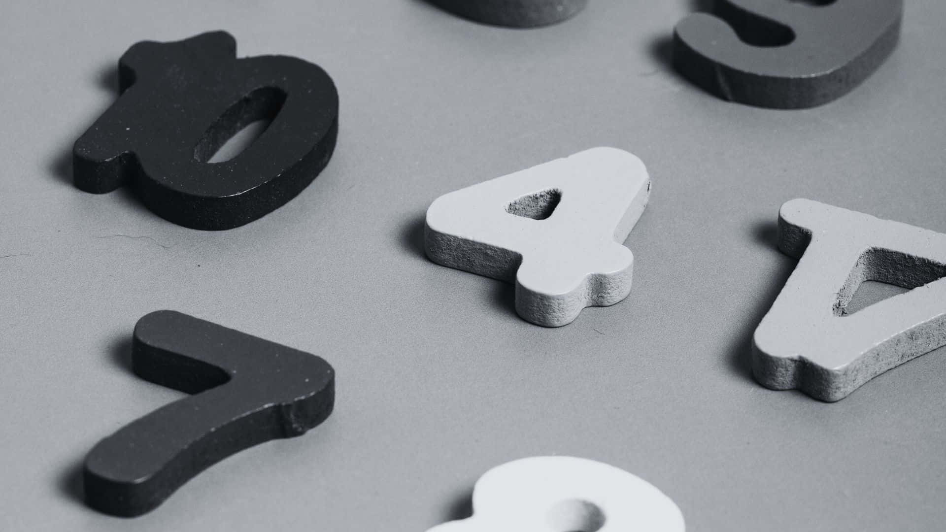 Black And White Number 桌布 壁紙 — 黑白3D數字剪影散落在灰色表面上，帶有柔和陰影。