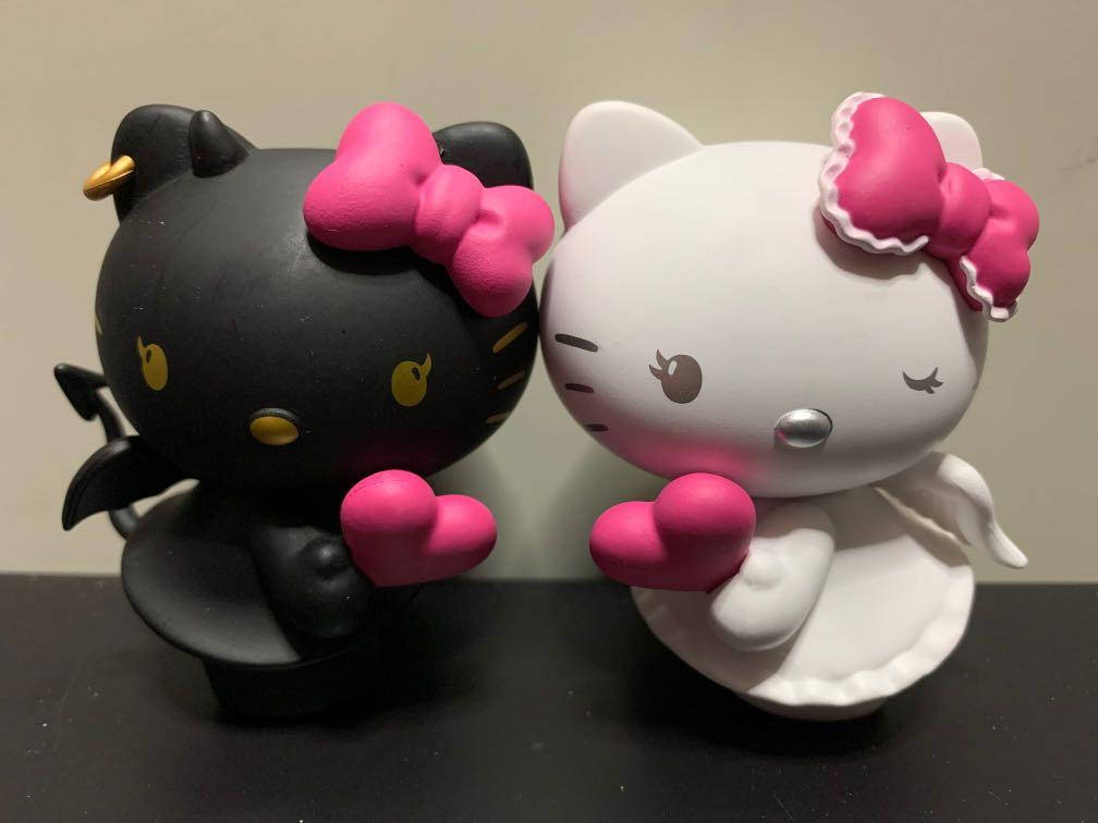 黑白Hello Kitty萬聖節 壁紙 — 兩個Hello Kitty公仔，一個黑色魔鬼，一個白色天使，都喺純色背景前拎住粉紅色心形。