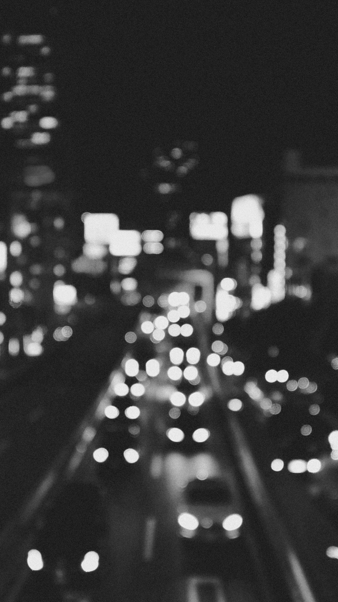 夜間模糊的城市街道，帶有發光的車燈和高樓大廈。