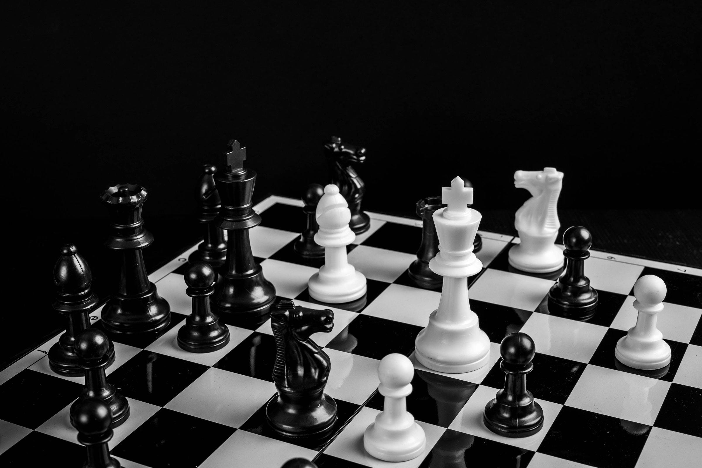 黑白塑膠棋子：智慧對決 壁紙 — 黑白棋子在棋盤上蓄勢待發，背景為 stark 的深色。