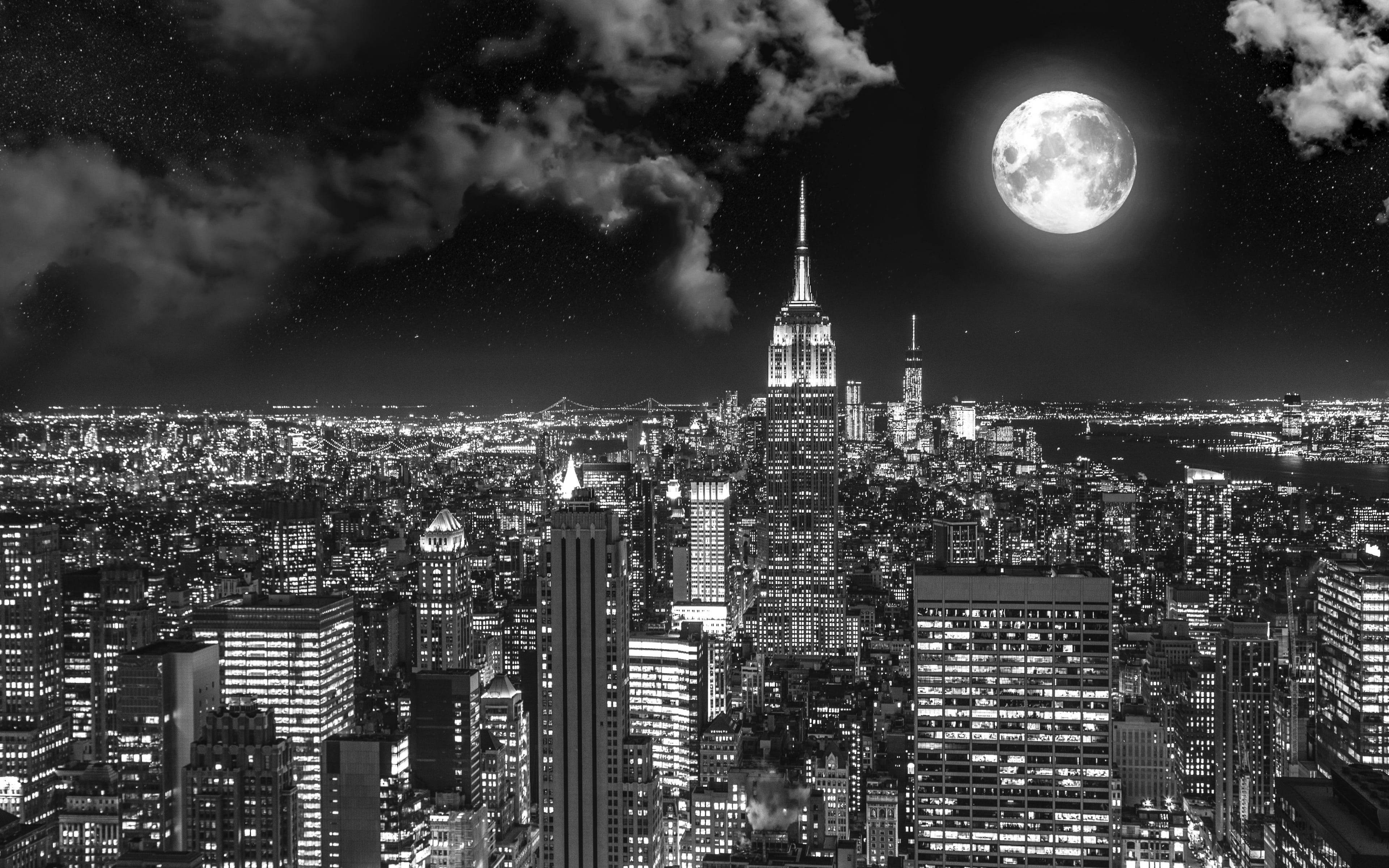 黑白 桌布 壁紙 — 黑白夜景城市景觀，滿月在摩天大樓和散落的雲層上方閃耀。