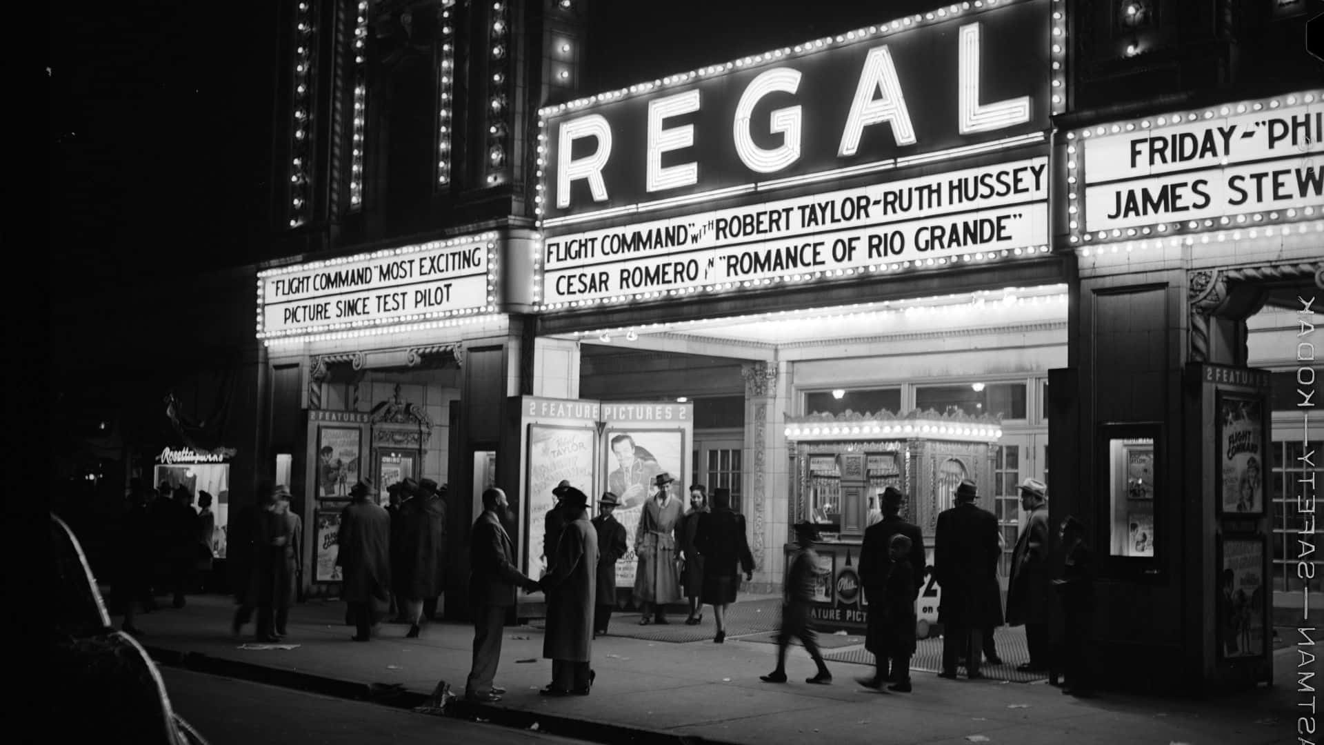 Black And White Movie 桌布 壁紙 — 黑白夜景拍攝，繁忙的復古Regal劇院招牌閃爍著電影片名，人群聚集在外。