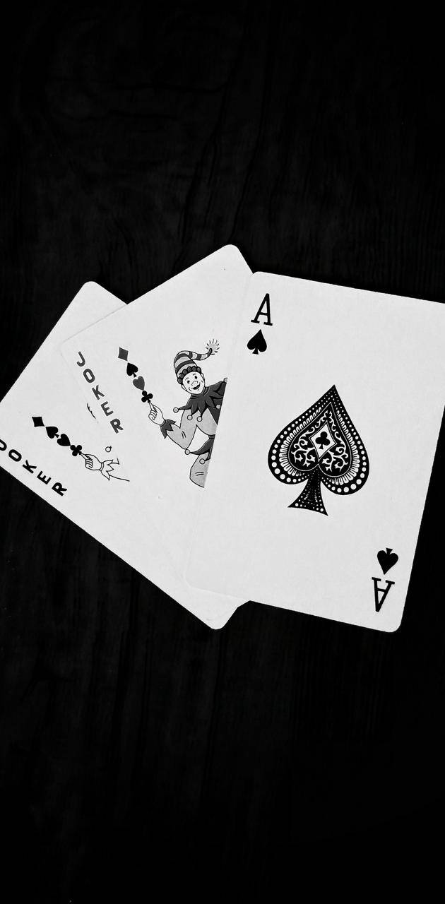 兩張啤牌，一張黑桃Ace和一張Joker，在深色木頭上。