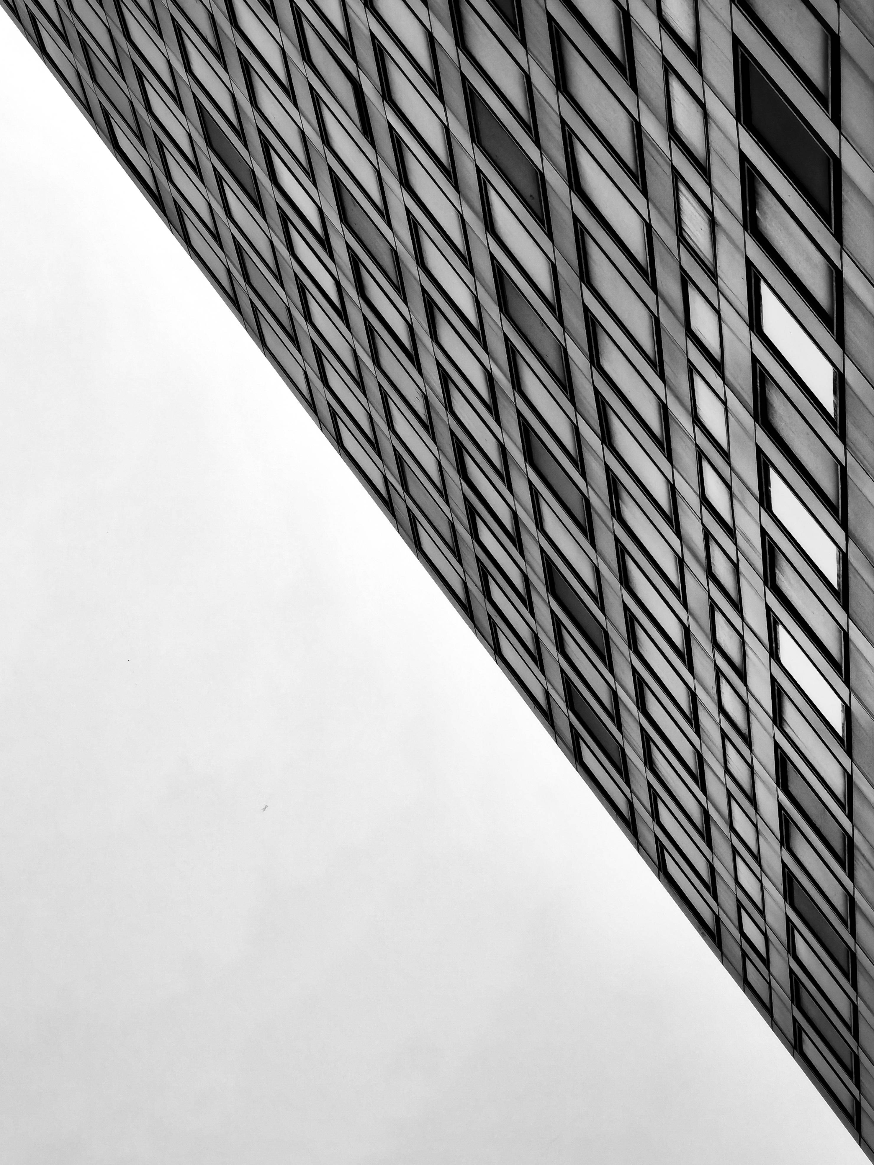 黑白建築 壁紙 — 一張以低角度拍攝的現代建築幾何外牆的鮮明黑白照片，背景是樸素的天空。