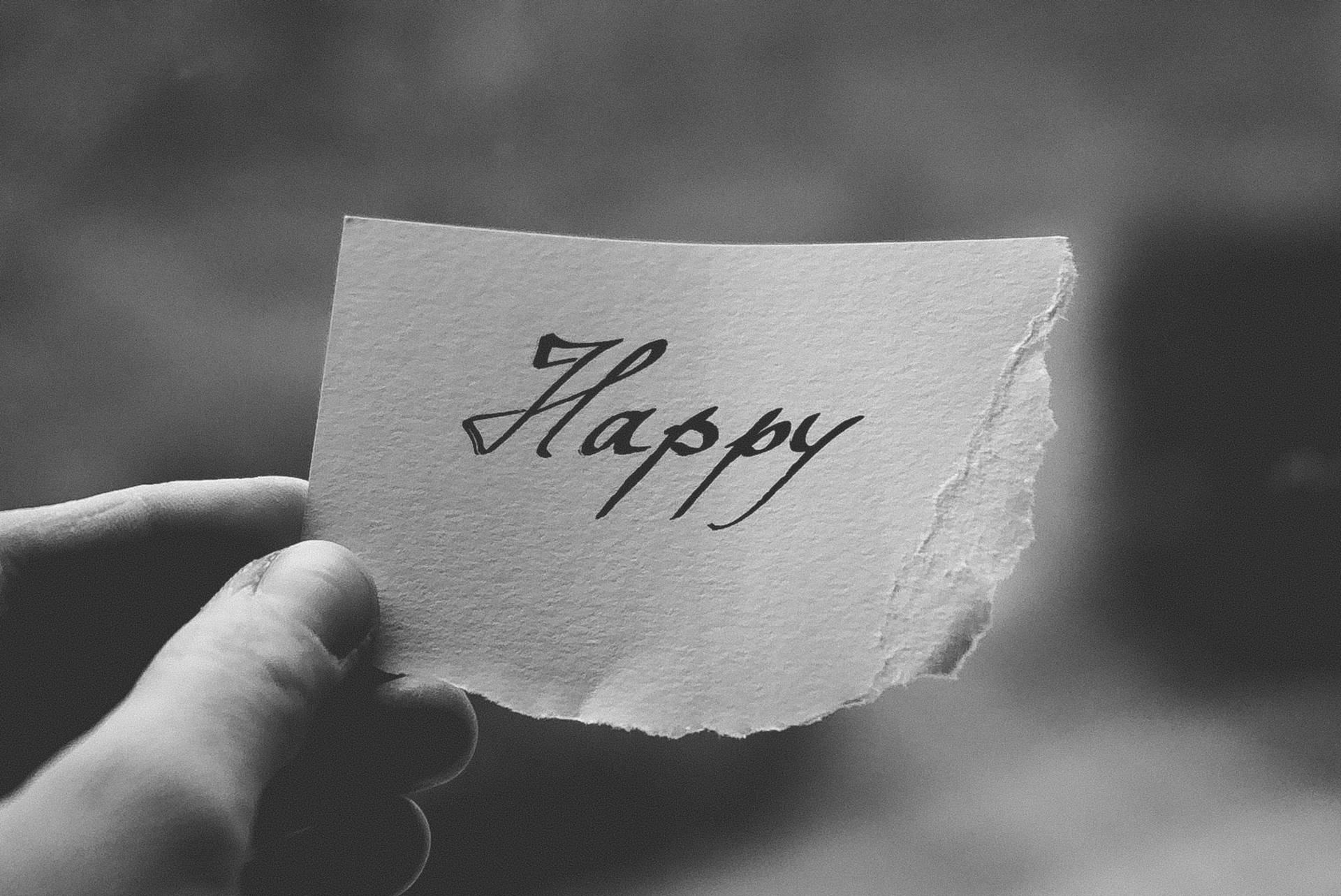 手拿撕破的紙，上面有手寫的 'Happy' 字樣，黑白配色。