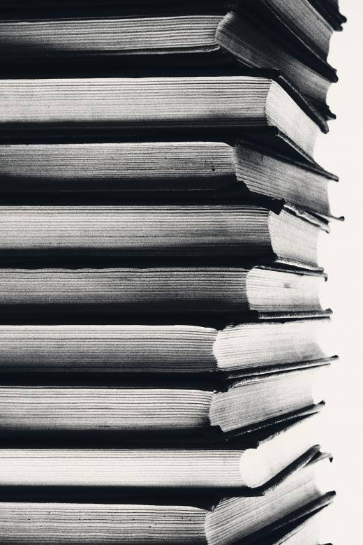 黑白垂直堆疊的書籍，書脊和書頁帶有紋理。