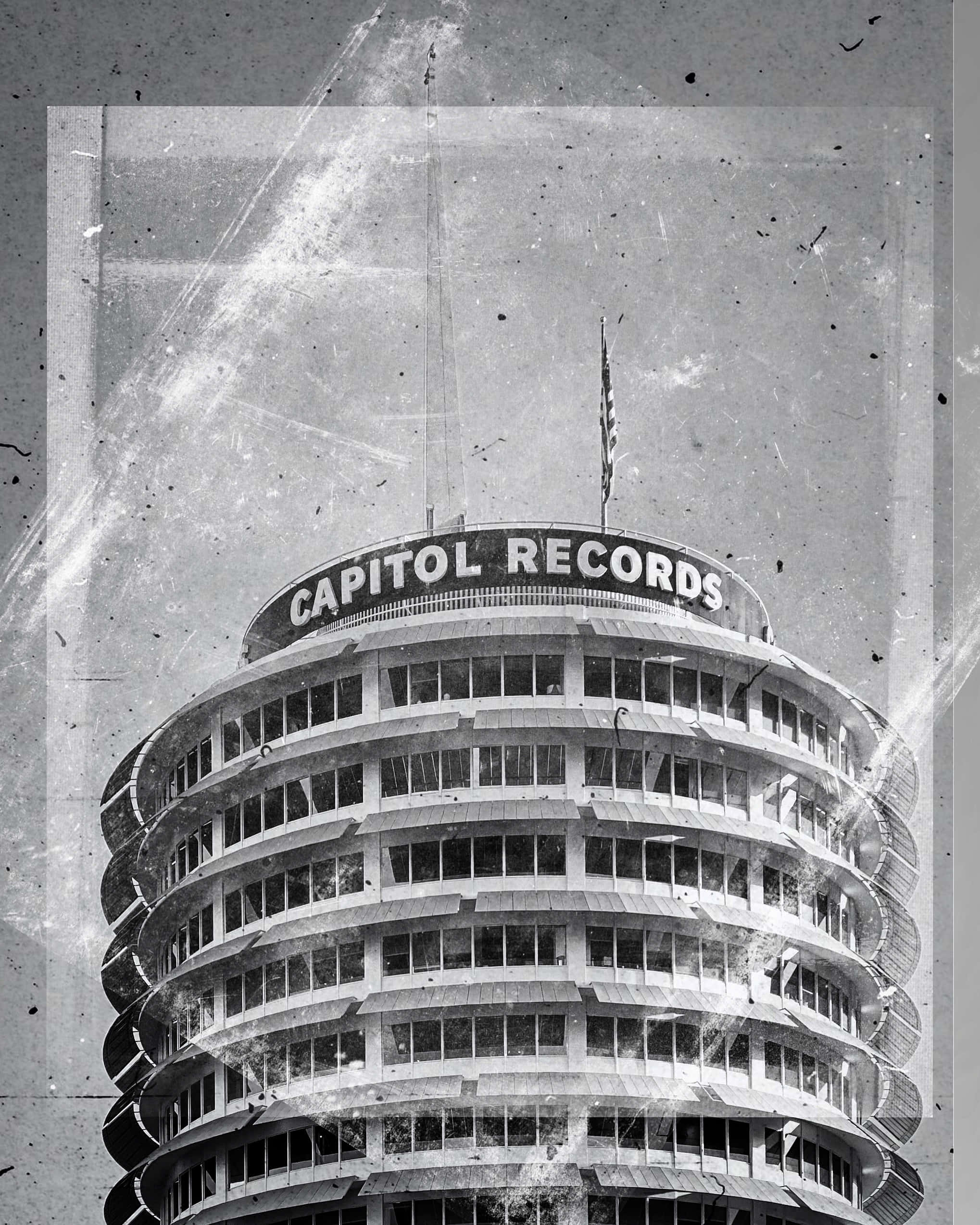 黑白框架中的卡皮托爾唱片大樓 壁紙 — 一張經典的 Capitol Records 大廈黑白復古照片，帶有可見的刮痕和灰塵。