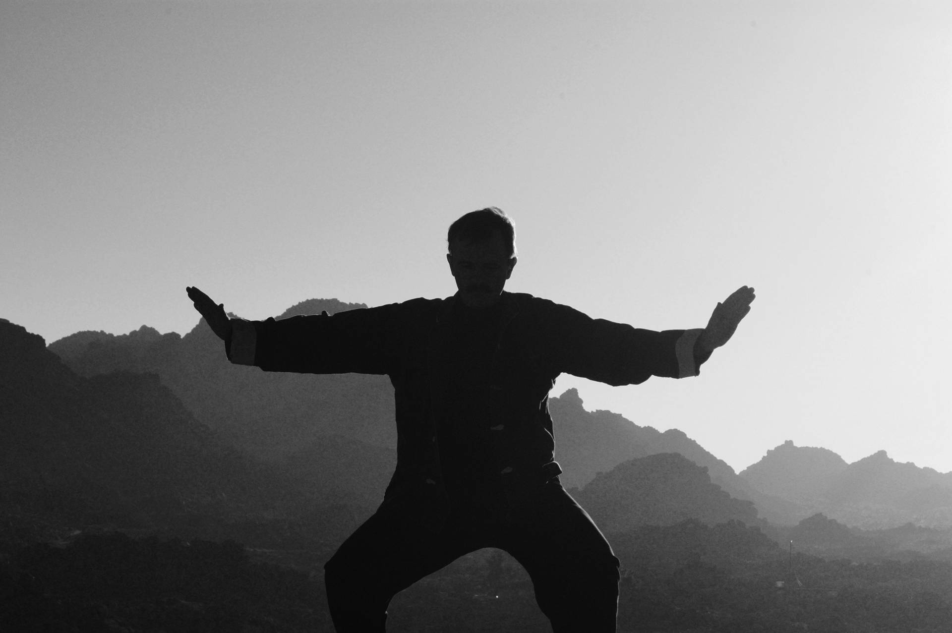 以山為背景，剪影人物練習武術。