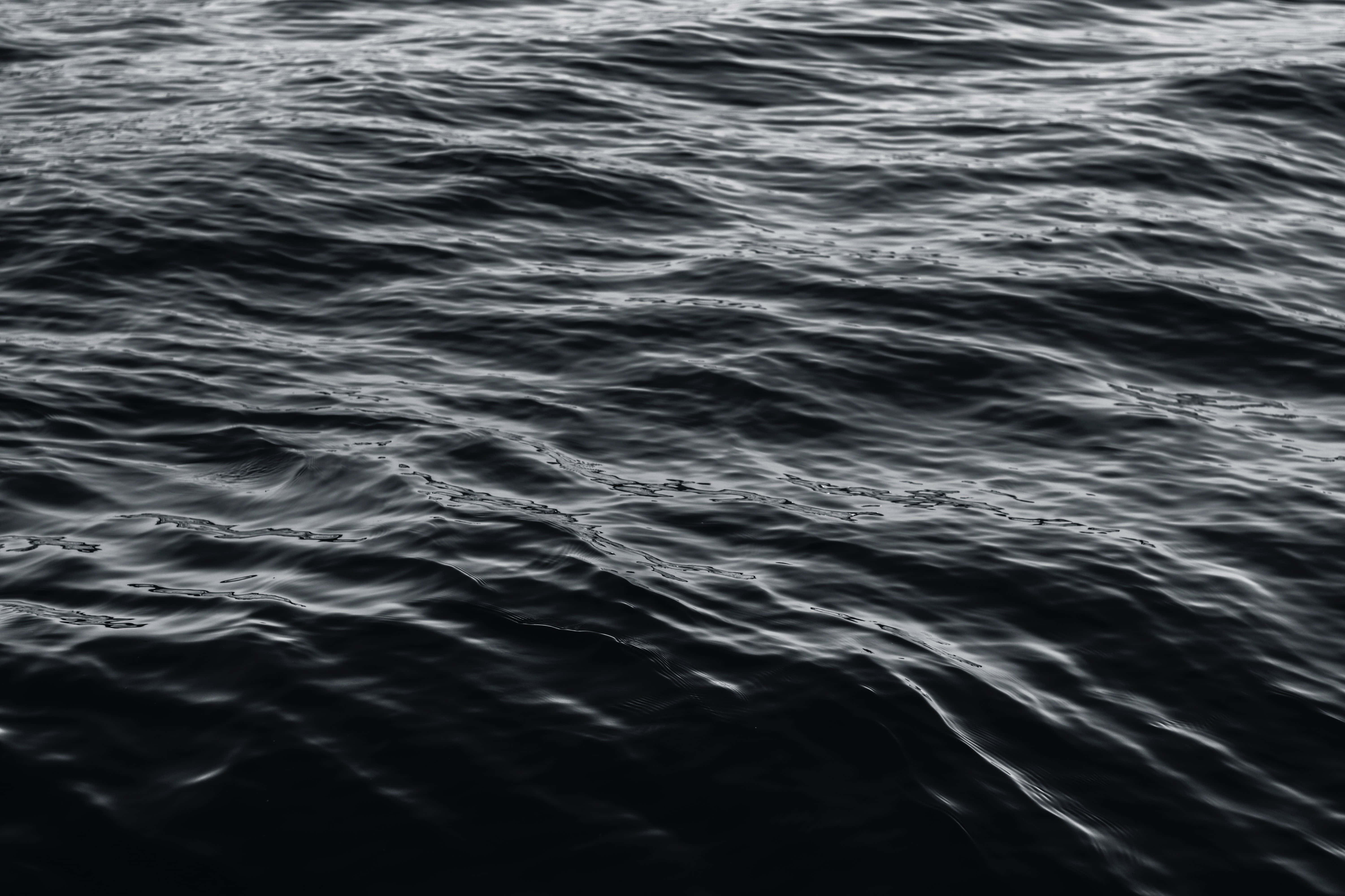 Dark Ocean 桌布 壁紙 — 黑白特寫，呈現紋理豐富的海浪，帶有微妙高光，在黑暗水面上反射光線。