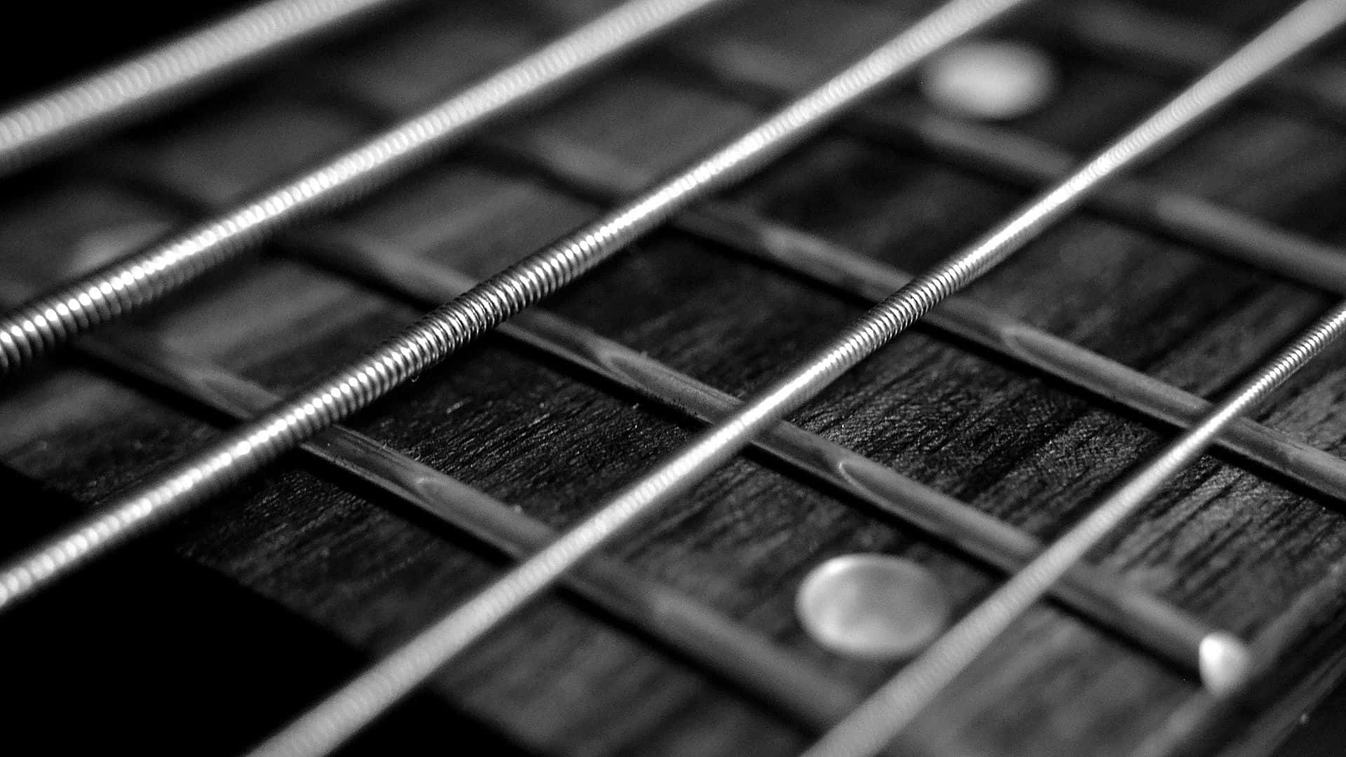 Black And White Guitar 桌布 壁紙 — 黑白特寫鏡頭，清晰對焦於穿過帶有金屬琴格的木製指板的結他弦。