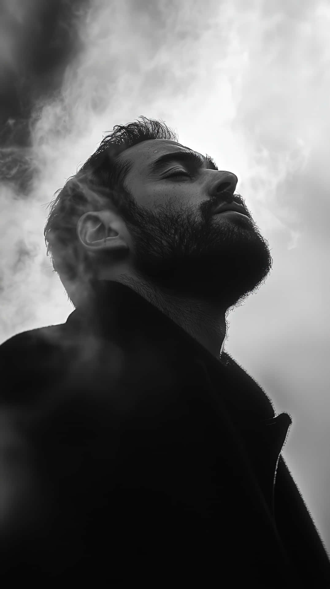 一個留鬍鬚的男人以剪影形式，穿過旋轉的煙霧向上凝視，背景是陰天。