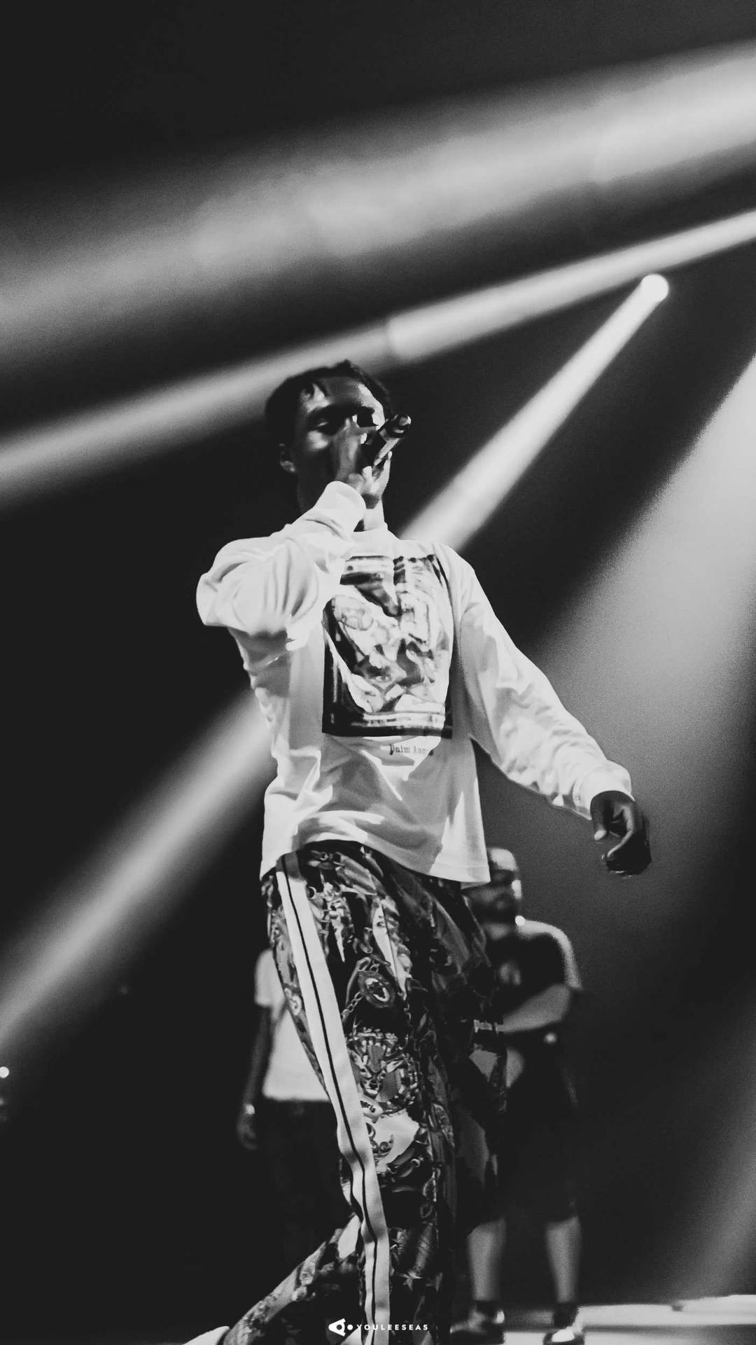 一位歌手在現場音樂會期間在明亮的聚光燈下在舞台上表演。 — 細路仔 GIF 壁紙