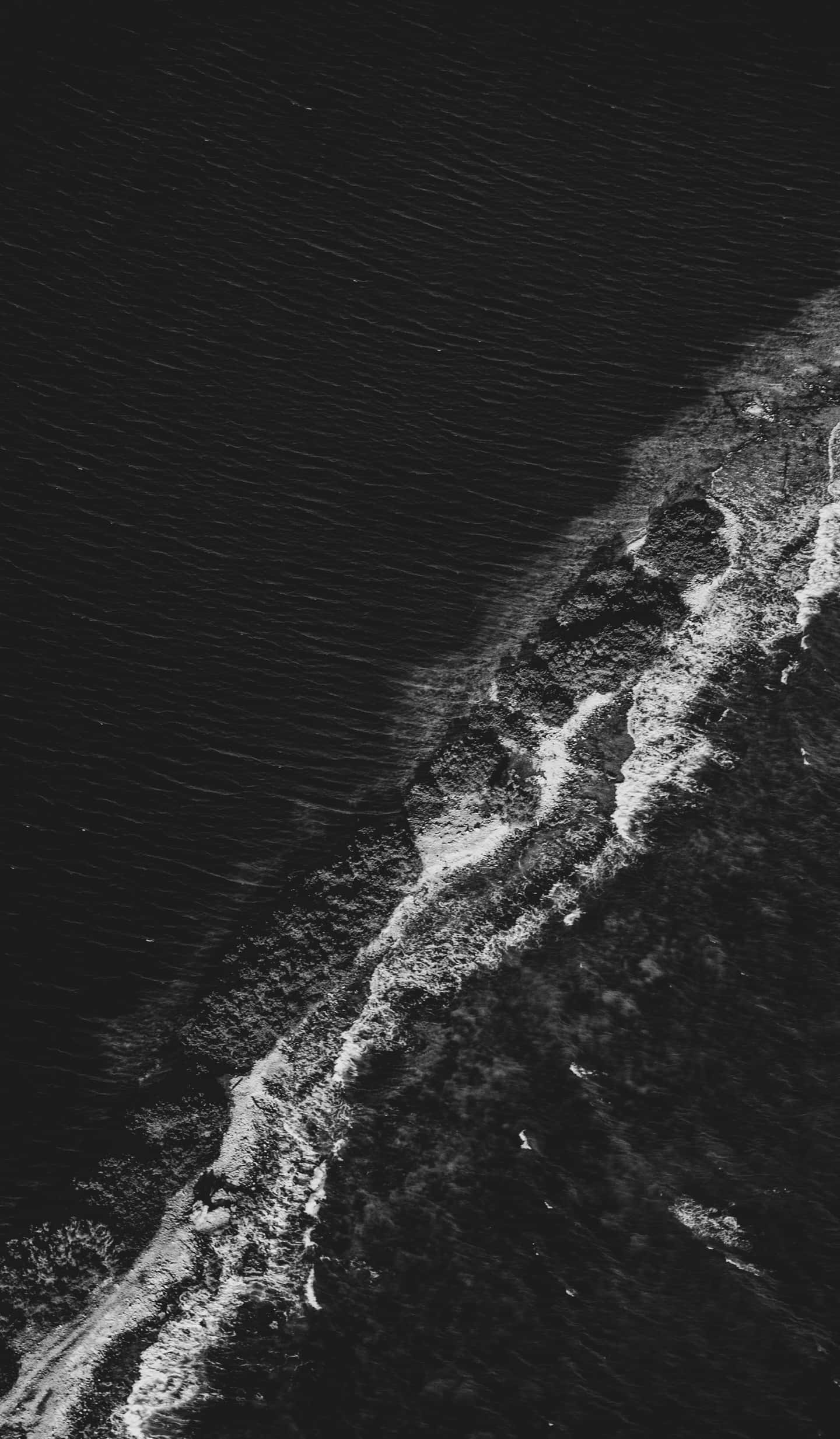 Black Sea 桌布 壁紙 — 黑白航拍視角，展現海浪拍打崎嶇海岸線，帶有紋理泡沫。