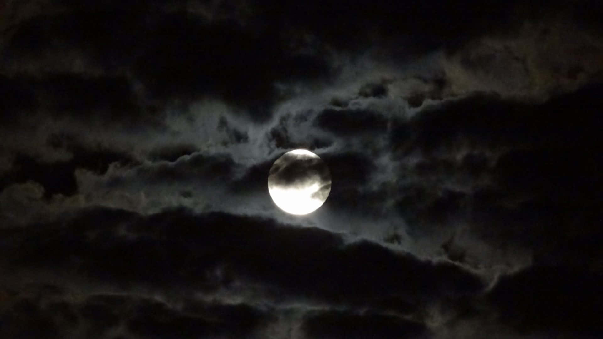 夜晚，滿月在黑暗的暴風雲後發光。