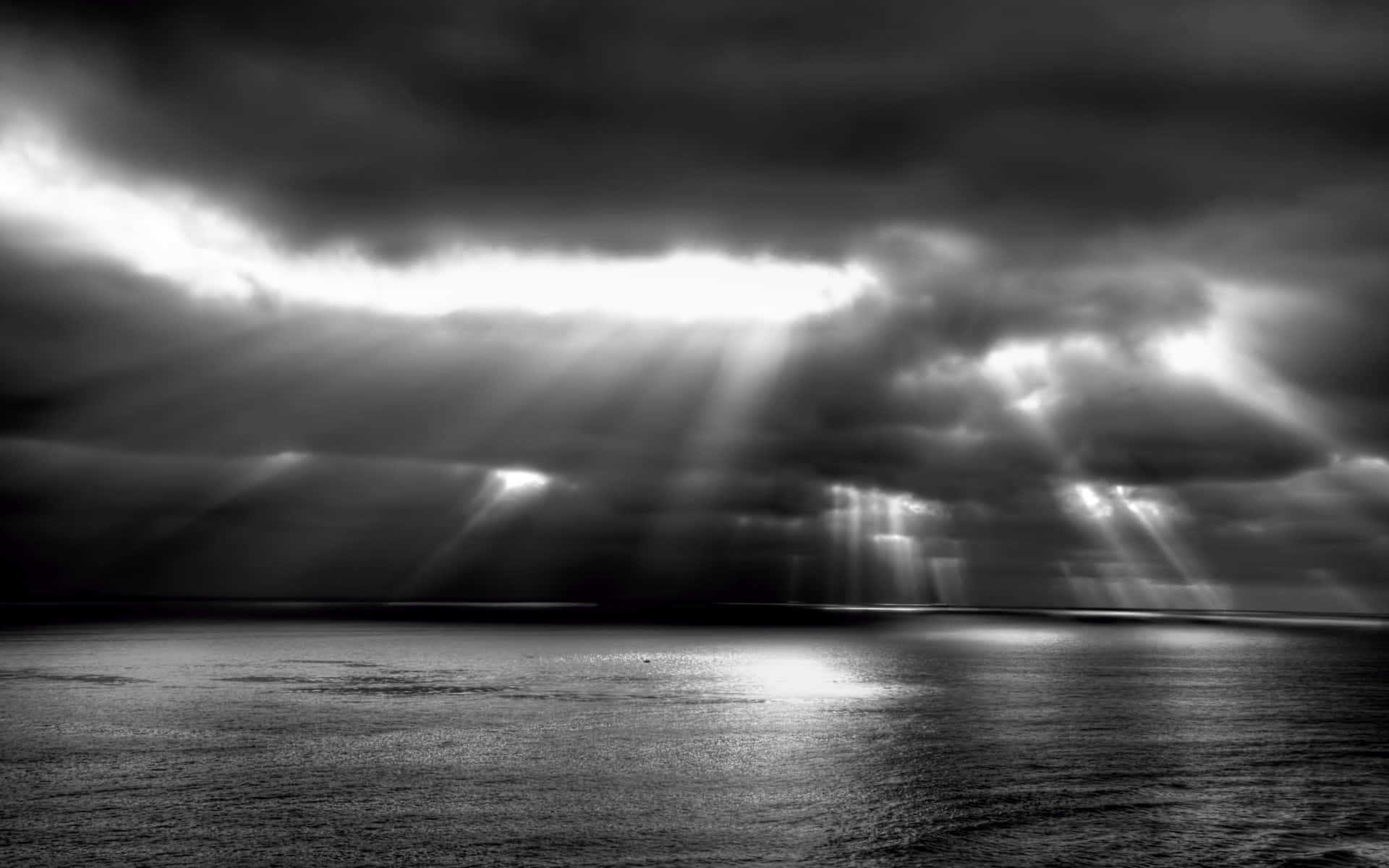 陽光光束穿透暴風雲，照射在平靜的海面上。