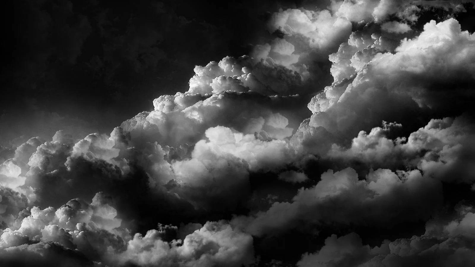 黑白雲朵桌面 壁紙 — 戲劇性的單色雲層在黑暗的天空中高對比旋轉，營造出陰鬱的氛圍場景。