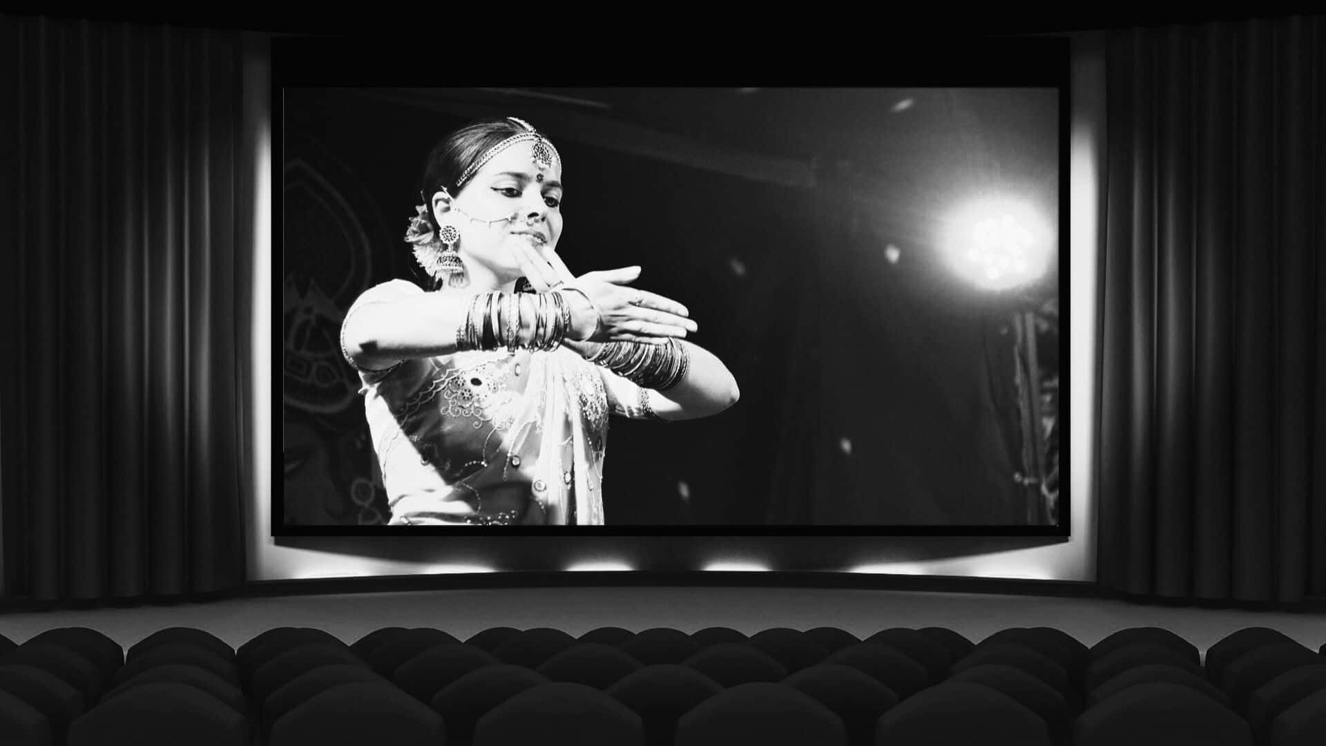 Black And White Movie 桌布 壁紙 — 黑白電影屏幕顯示一位穿著傳統服飾的優雅舞者在舞台上以戲劇性燈光表演。