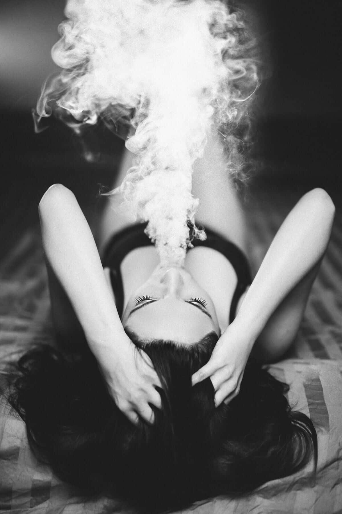 女士躺下閉眼呼出煙霧的黑白照片。