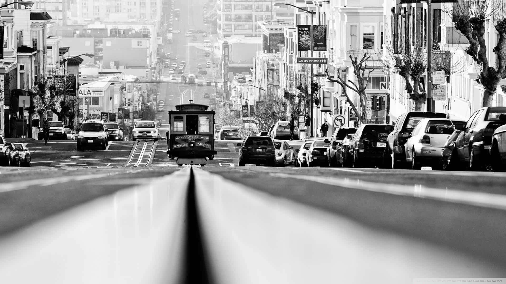 黑白照片顯示一輛纜車正在爬升一條停滿汽車的陡峭城市街道。