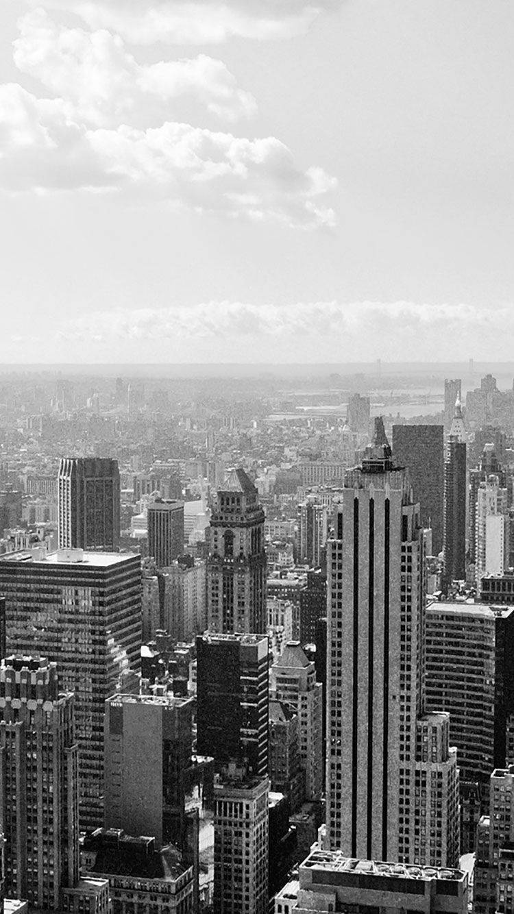 Skyscraper 桌布 壁紙 — 黑白鳥瞰圖，展示雲層下高樓林立的密集城市天際線。