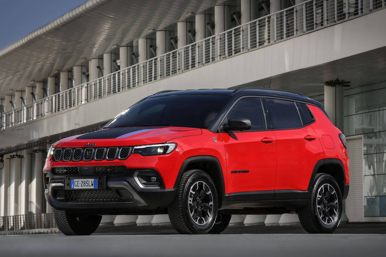 紅色Jeep Compass SUV停放在現代白色建築結構下。