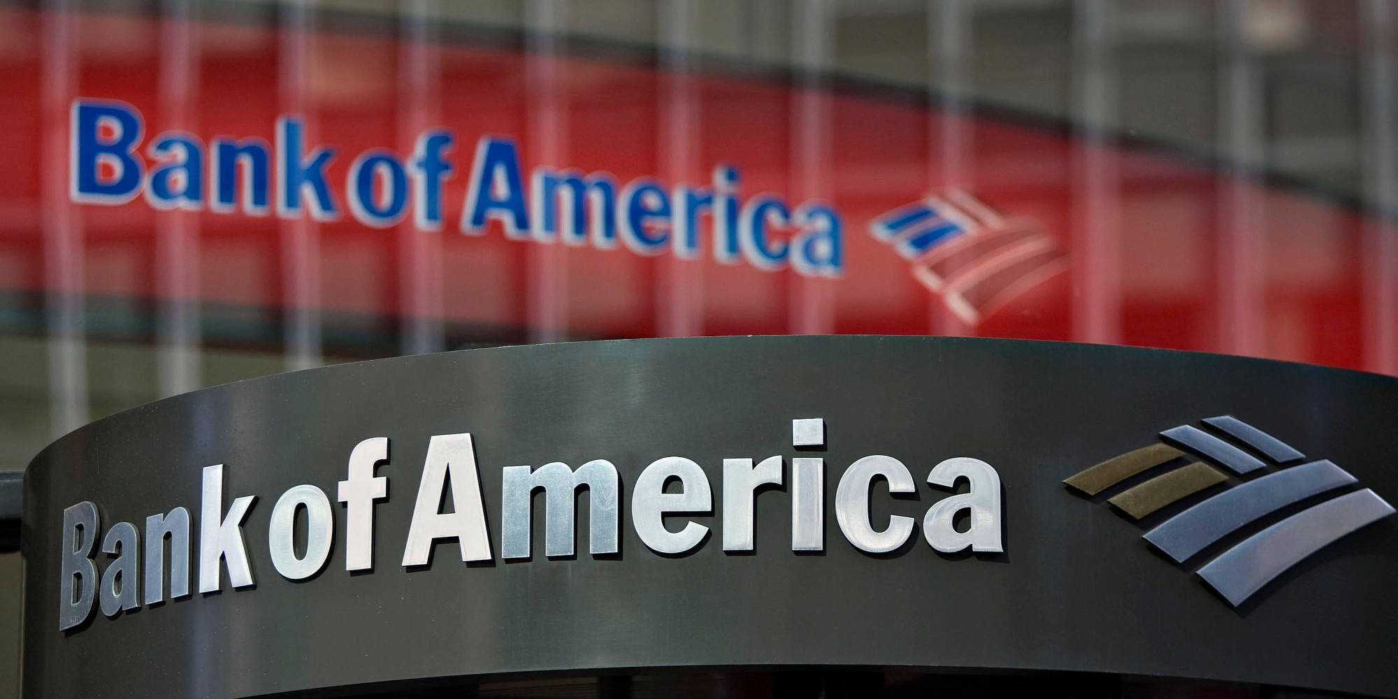 黑紅配色美國銀行招牌 壁紙 — 特寫鏡頭：一個時尚的 Bank of America 標誌，帶有金屬字體和標誌，背景為模糊的紅色。