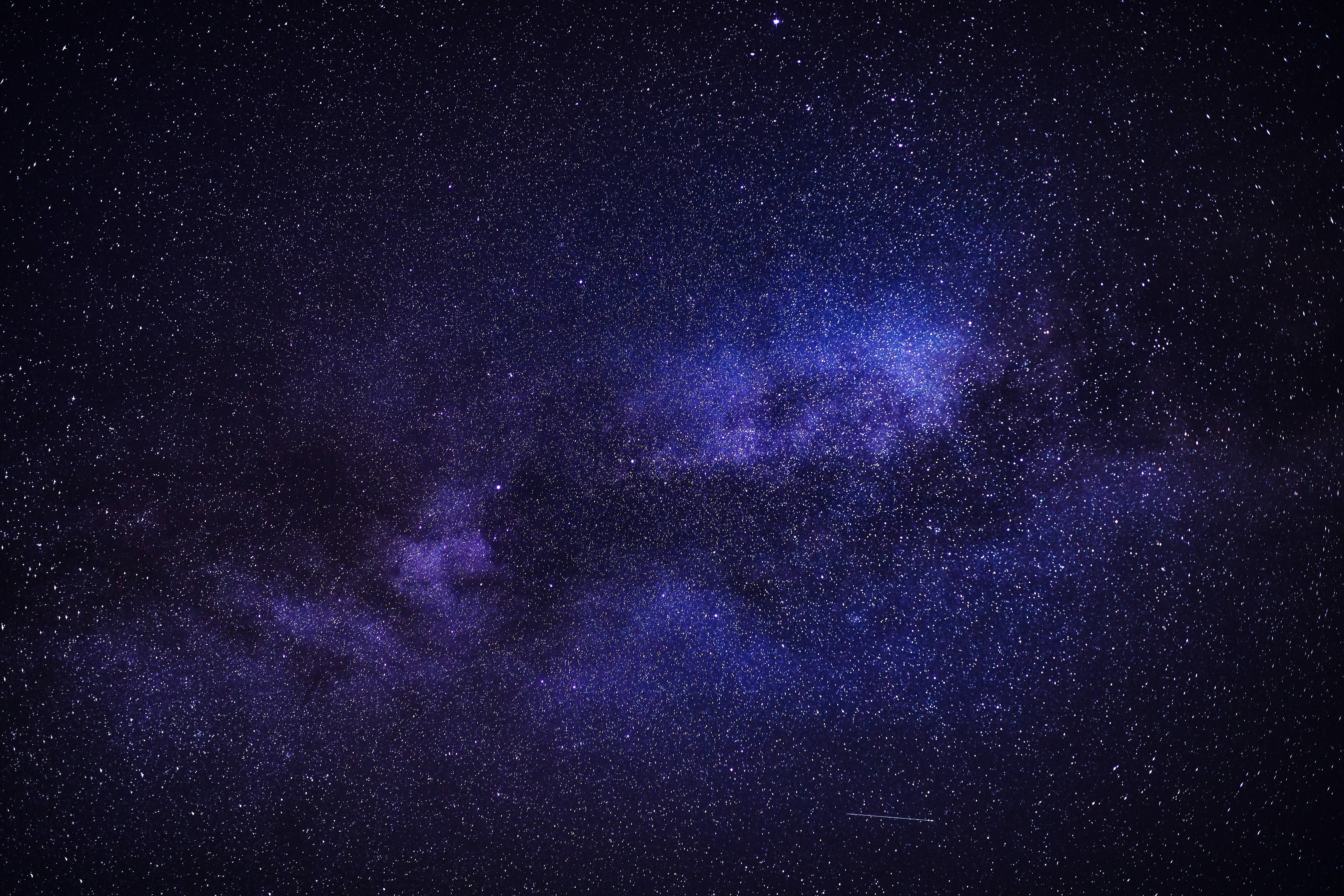 黑紫調星雲風景 壁紙 — 令人嘆為觀止的銀河系景觀，在深紫色和藍色中閃耀，映襯著繁星點點的夜空。