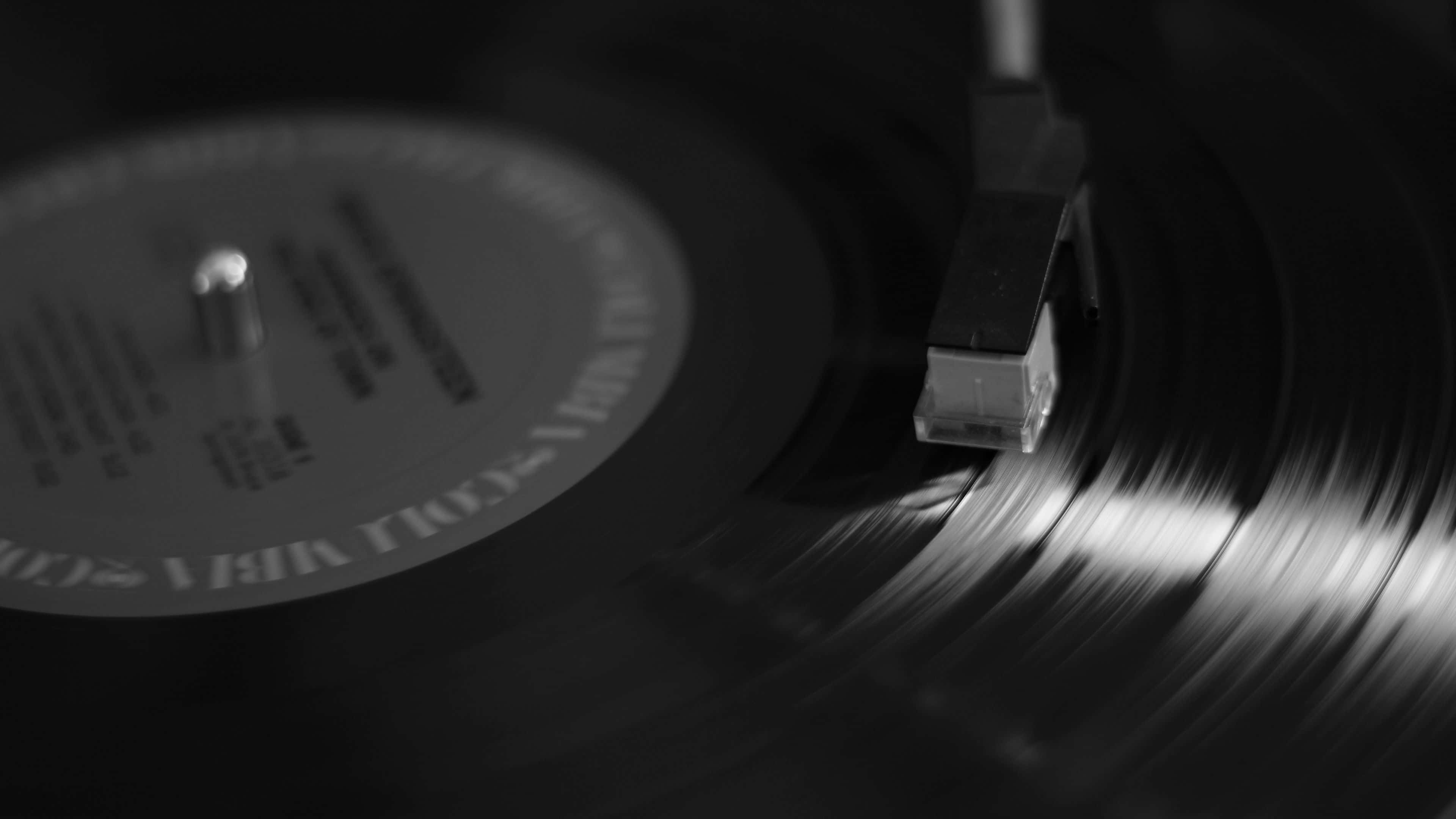 record 桌布 壁紙 — 黑膠唱片在唱盤上旋轉的單色特寫，唱針輕輕放在唱片坑紋上。