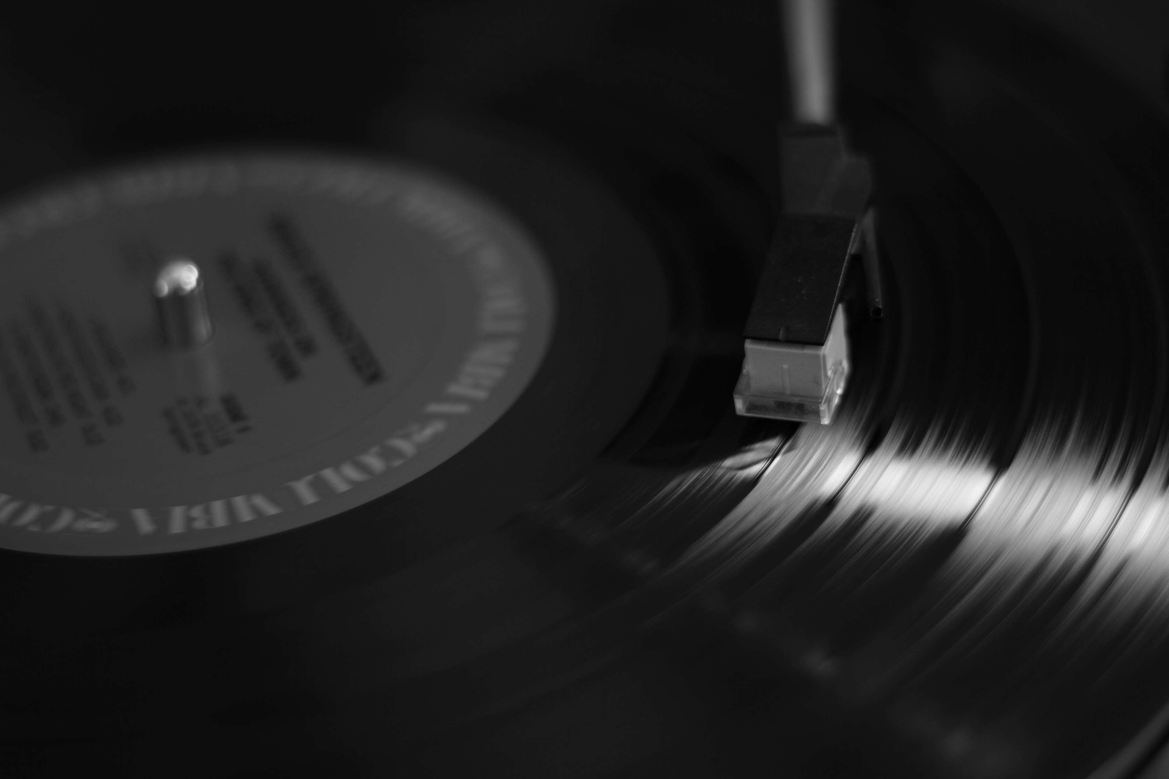 record 桌布 壁紙 — 黑膠唱片在唱盤上旋轉的單色特寫，唱針輕輕地沿著其凹槽移動。