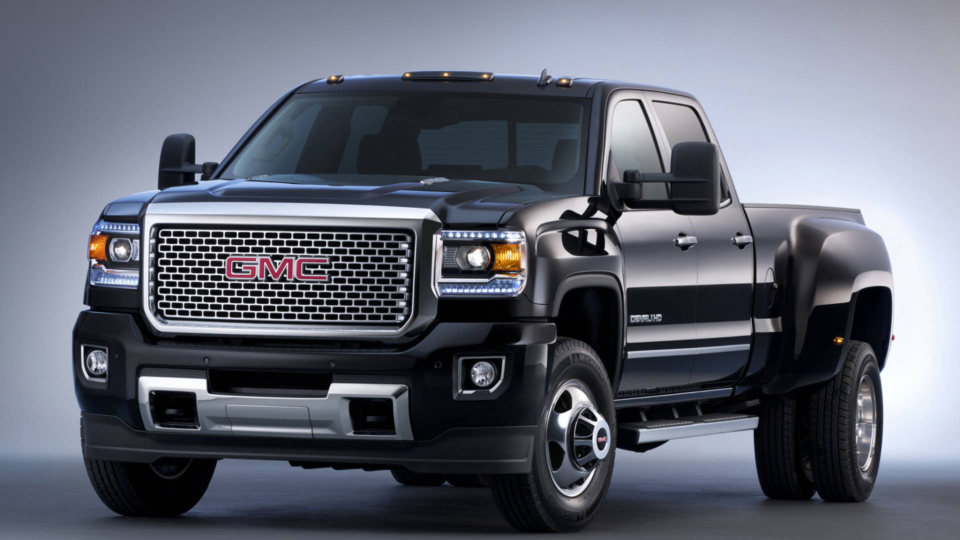 黑色 GMC Sierra 雙輪設計 壁紙 — 一輛時尚的黑色 GMC Sierra Denali 皮卡車，帶有鍍鉻飾邊和 LED 頭燈，在漸變灰色工作室背景前擺姿勢。