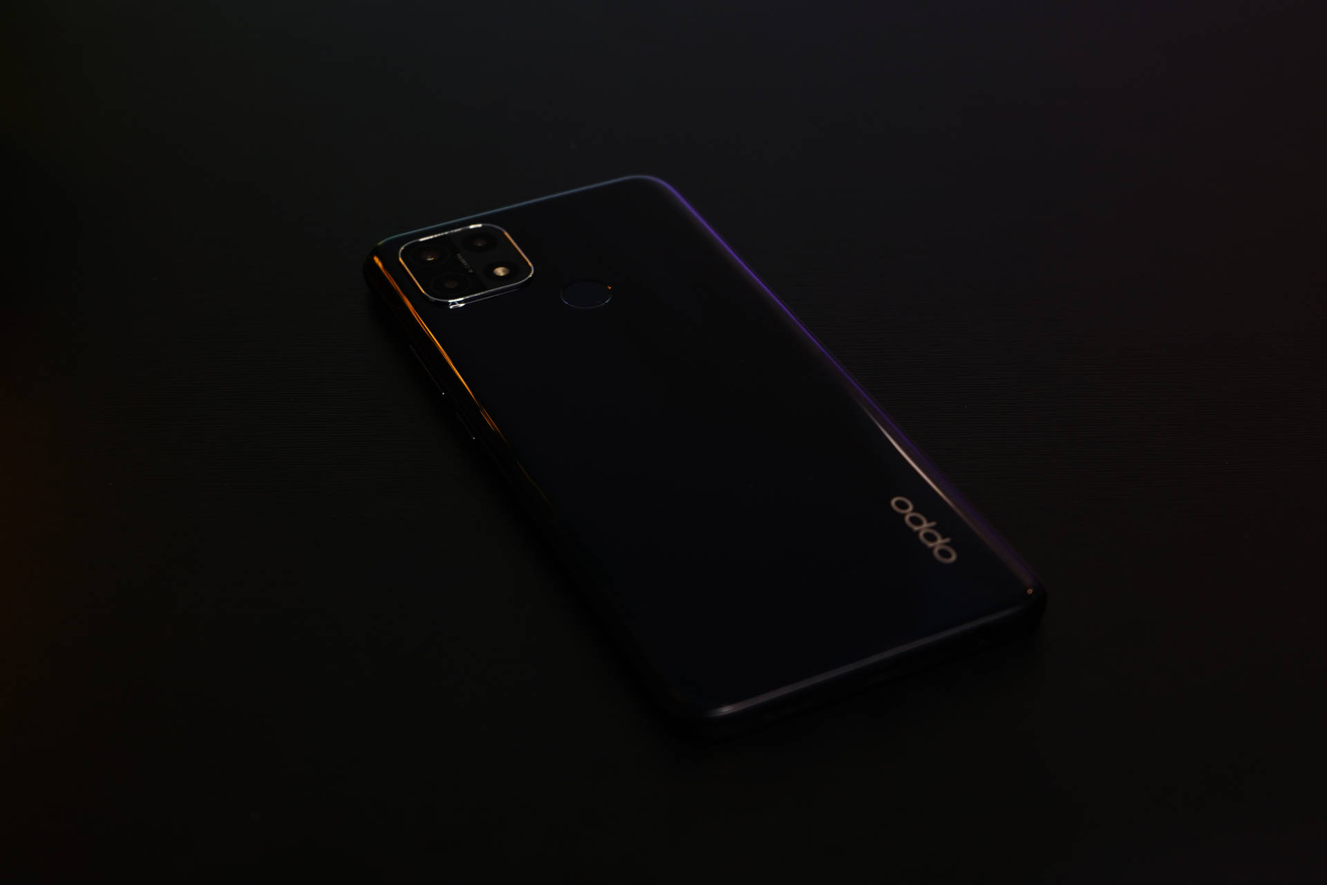 一部黑色 OPPO 智能手機，帶有光面機身，放置在黑暗的表面上。