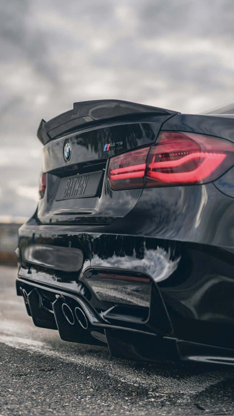 黑色BMW M5跑車，配備紅色尾燈和四出排氣管，在潮濕的路面上。