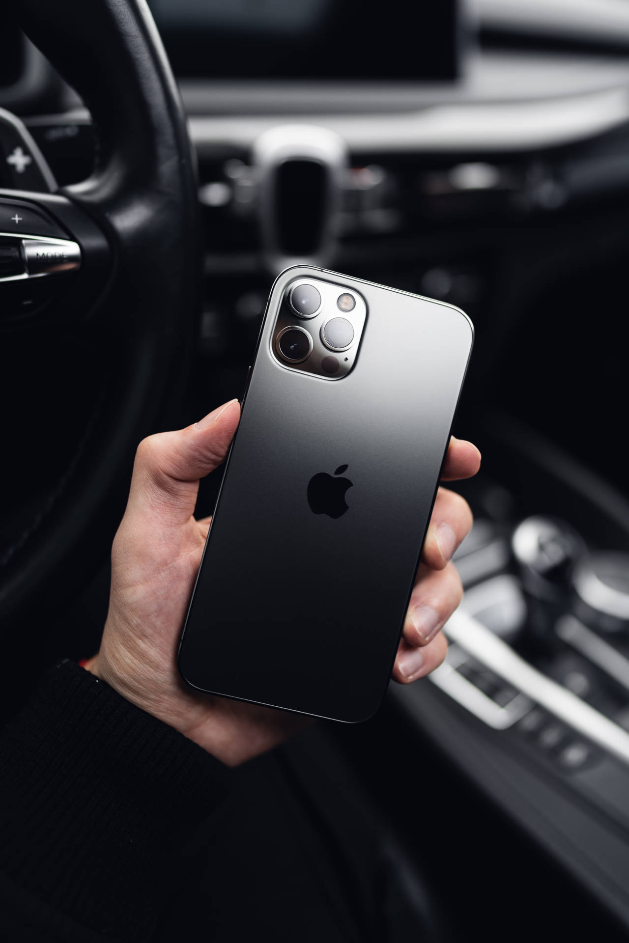 手在豪華車內拿著黑色iPhone 12 Pro Max。
