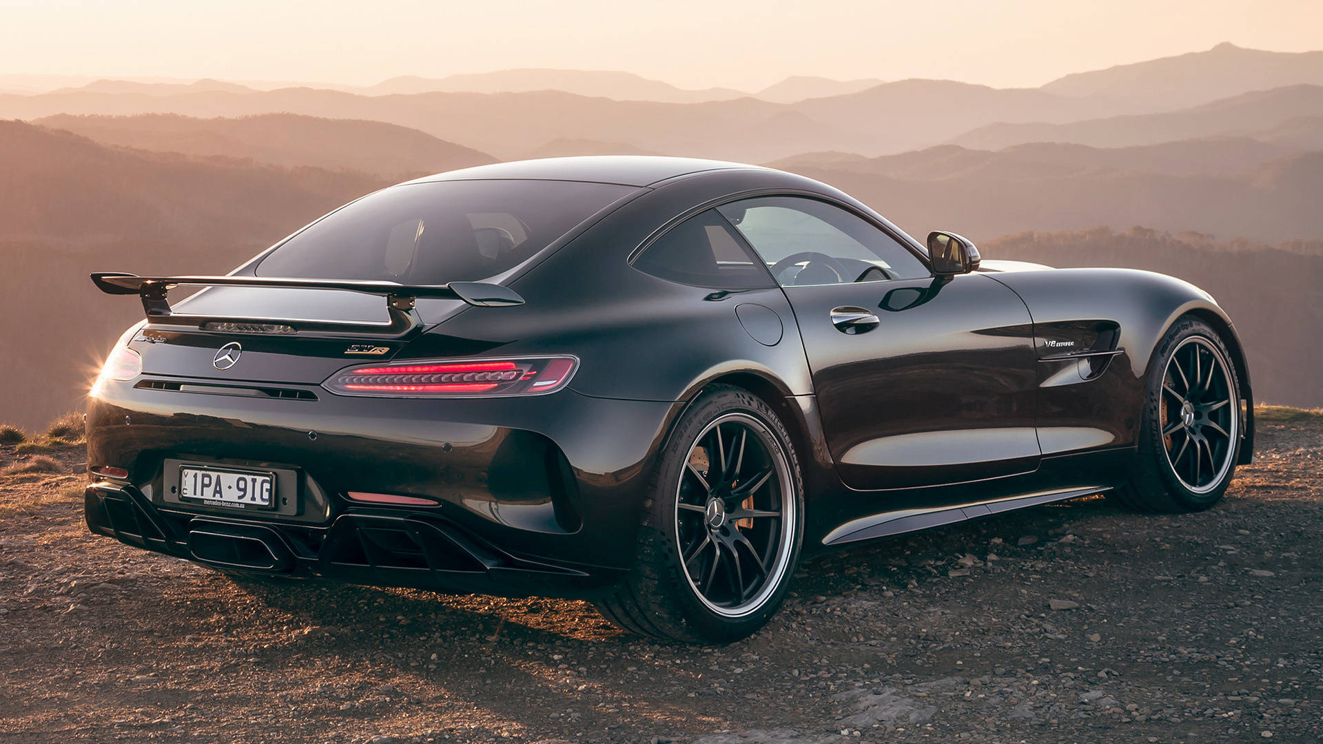 黑色Mercedes-AMG GT跑車停在日落時分的山頂觀景點。