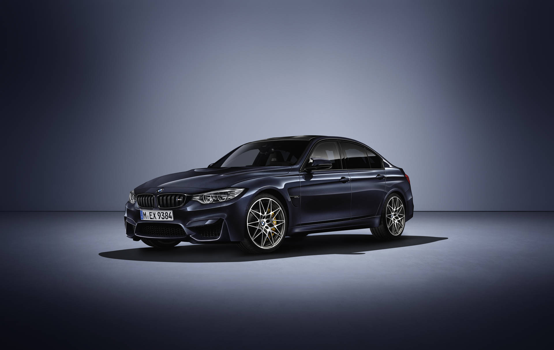 深藍色BMW M3轎車，金色輪圈，在工作室環境中。