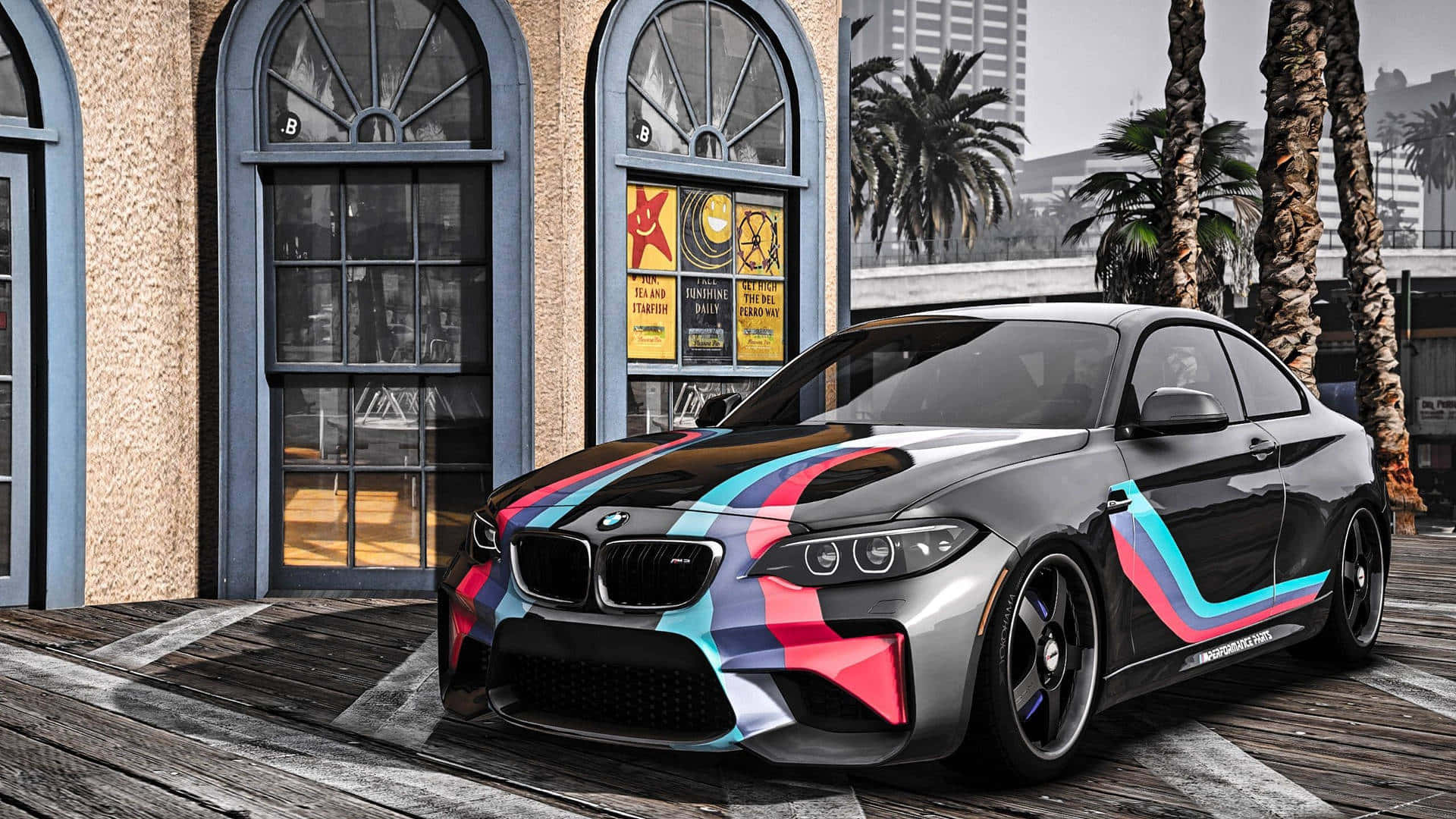 黑色BMW M2 1920x1080 M系列背景 壁紙 — 一輛時尚的黑色BMW M2雙門轎跑車，帶有鮮豔的粉紅、藍和白賽車條紋，停泊在木製碼頭上，旁邊有棕櫚樹和一座復古建築。