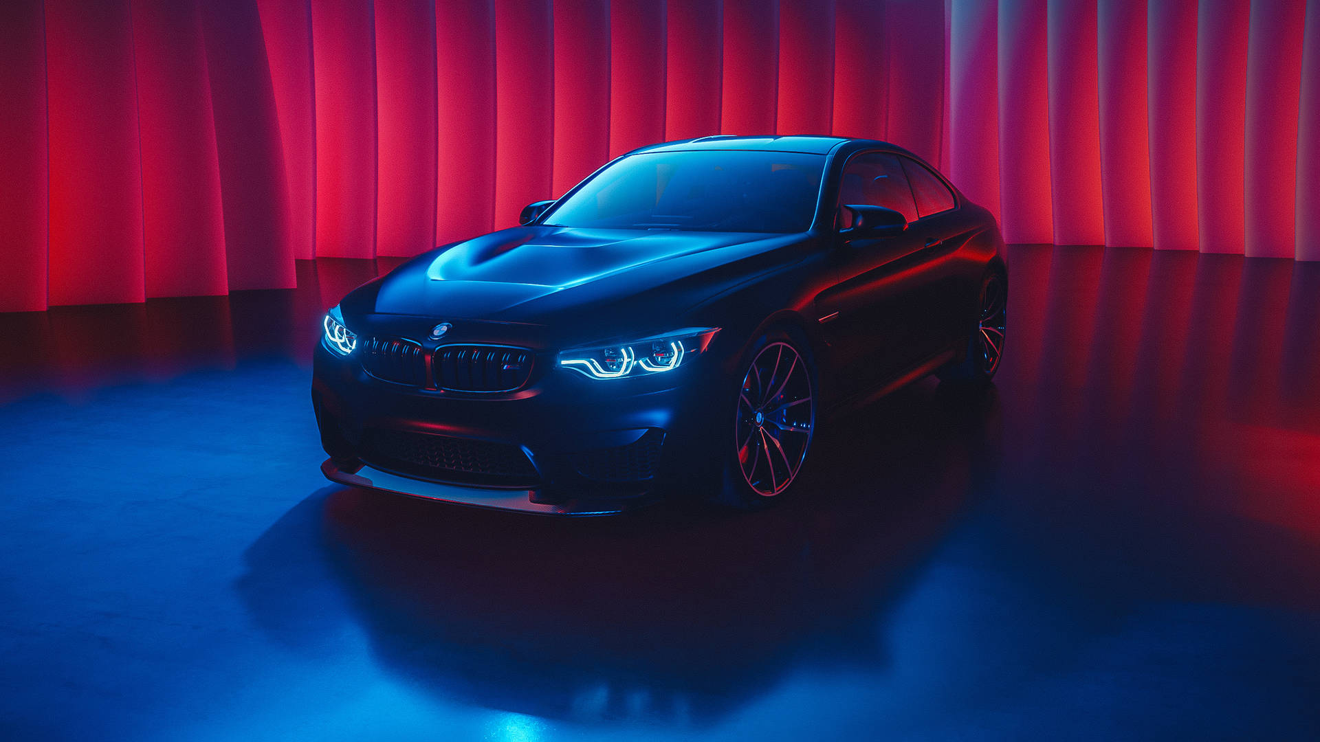 黑色BMW跑車在帶有窗簾背景的工作室中被紅色和藍色燈光照亮。