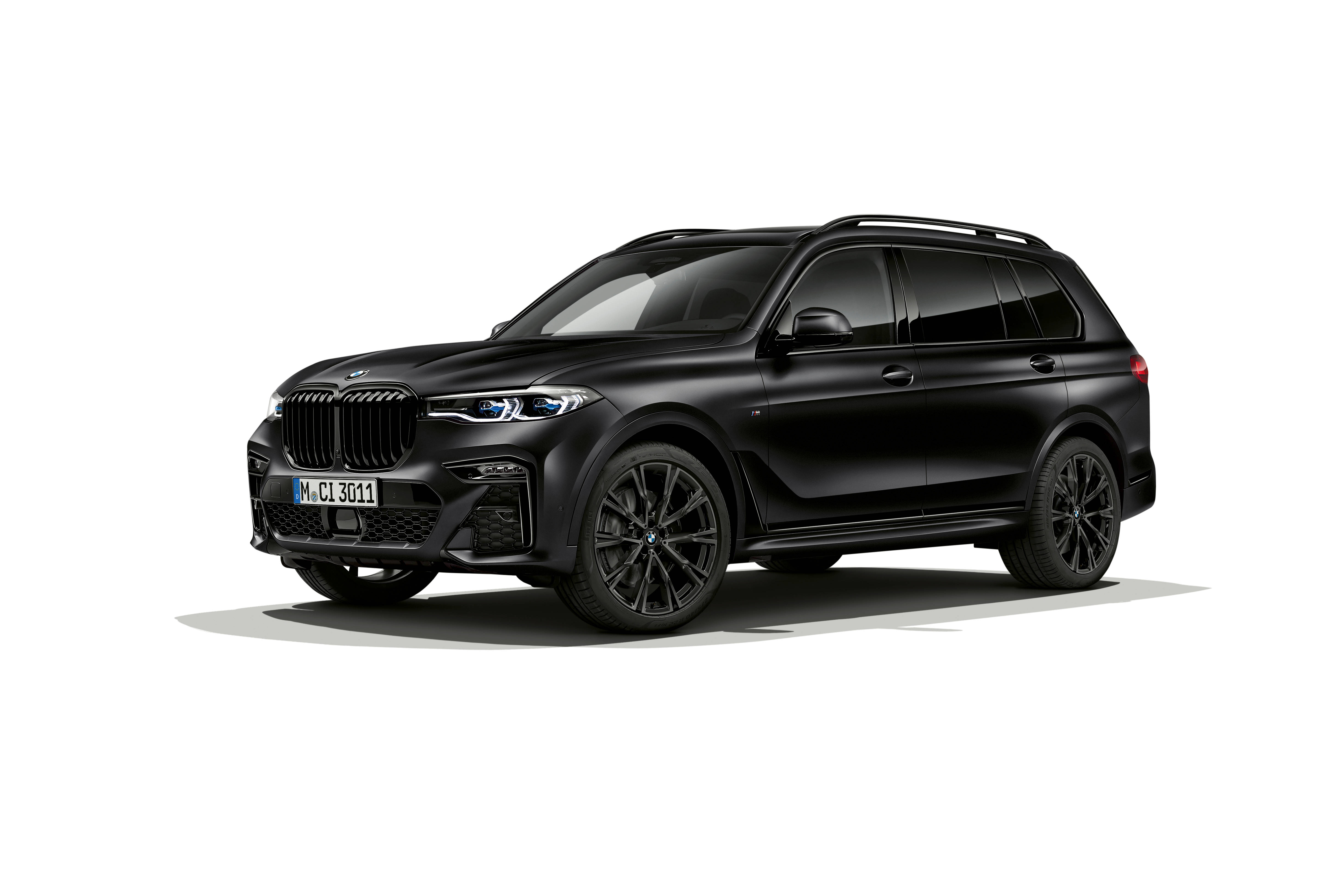 黑色BMW X7側影 壁紙 — 一輛時尚的啞光黑色BMW X7 SUV在工作室燈光下以乾淨的白色背景展示。