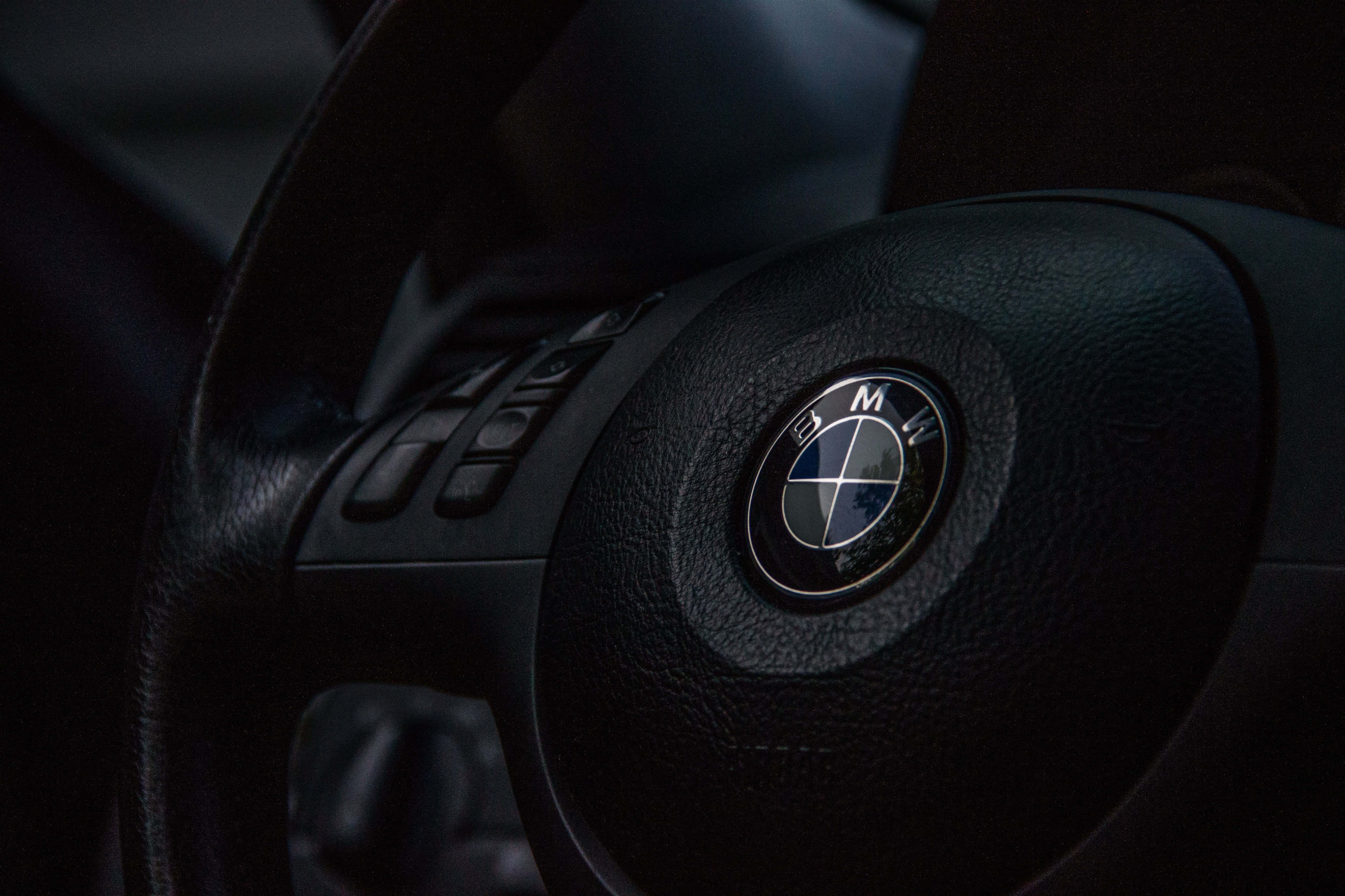 Bmw Logo 桌布 壁紙 — 黑色BMW軚盤特寫，採用紋理皮革，在昏暗燈光下帶有發光標誌。