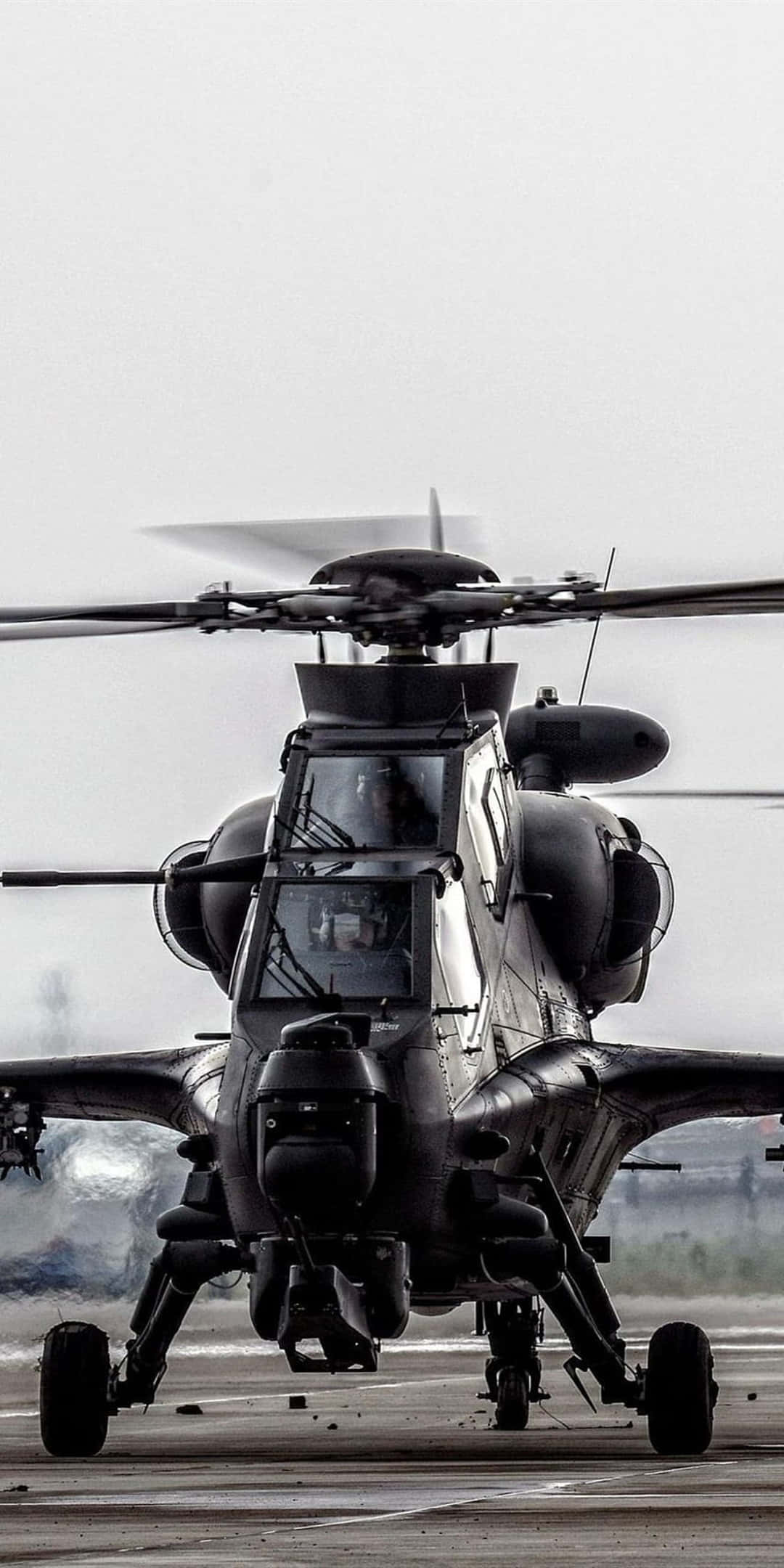 黑色CAIC Z-10直升機 - Pixel 3背景 壁紙 — 一架軍用直升機旋轉著螺旋槳，停在停機坪上，天空多雲，黑白畫面。