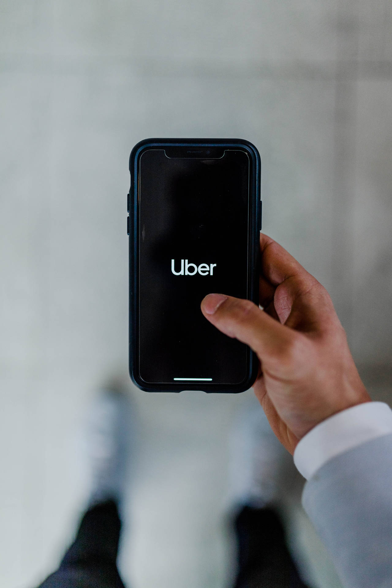 手拿著手機，屏幕上顯示Uber應用程式標誌