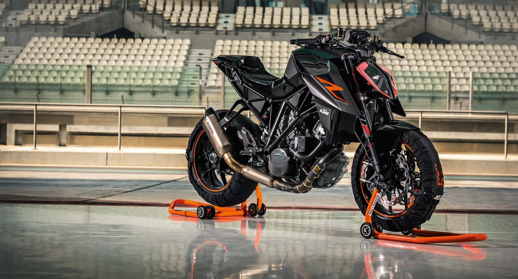 黑色KTM 1290 Super Duke R停於白色空曠體育場照片 壁紙 — 一架時尚的黑色和橙色KTM電單車停放在空蕩蕩的體育館內明亮的橙色支架上，地板具有反射效果。