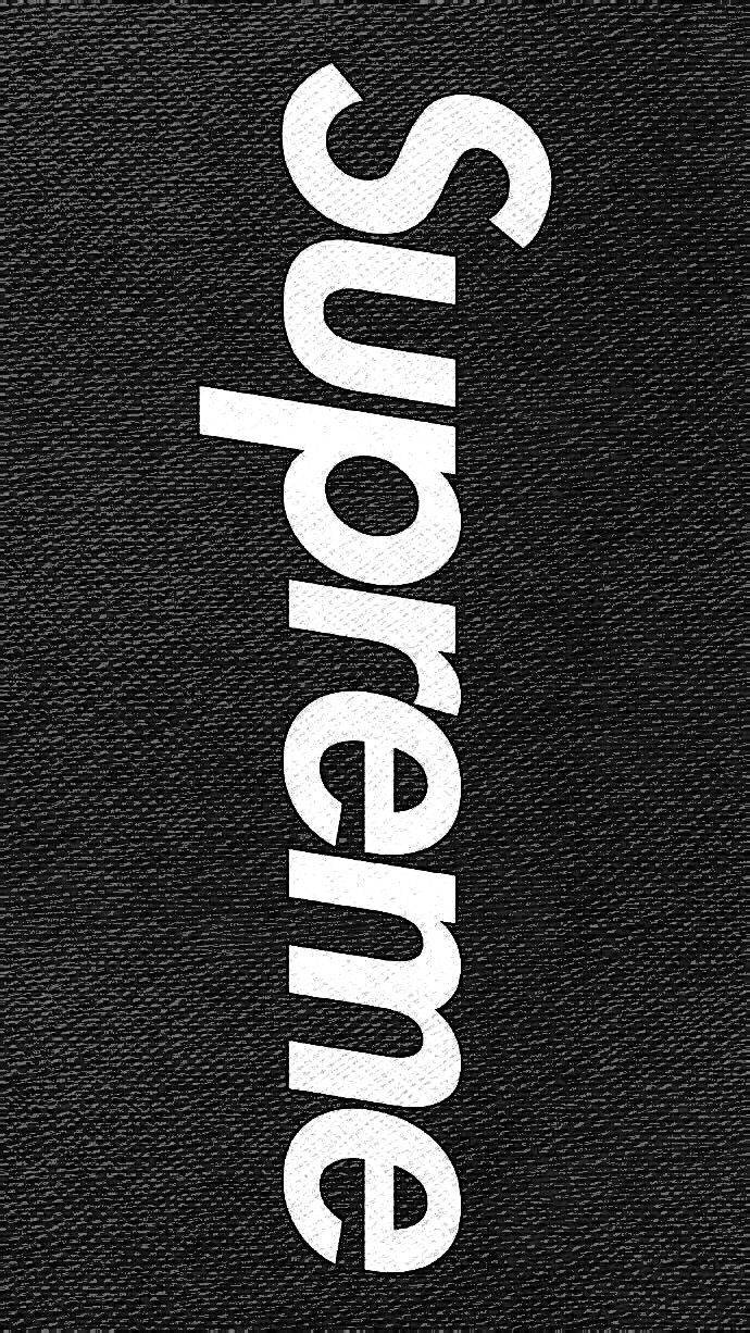 黑色Supreme配酸洗效果 壁紙 — 粗體白色 'Supreme' 標誌垂直排列在紋理黑色布料背景上。