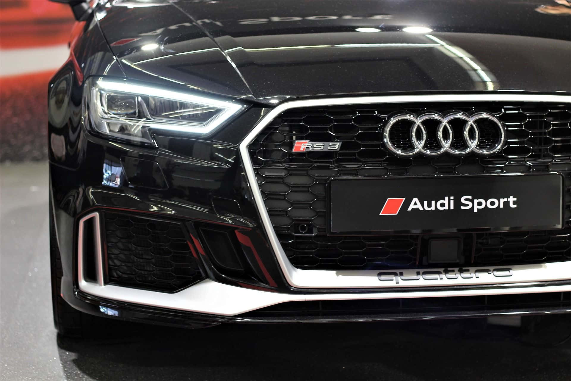 Audi Rs3 桌布 壁紙 — 黑色亮面Audi RS3前格柵、亮起頭燈及Audi Sport徽章的近距離特寫。
