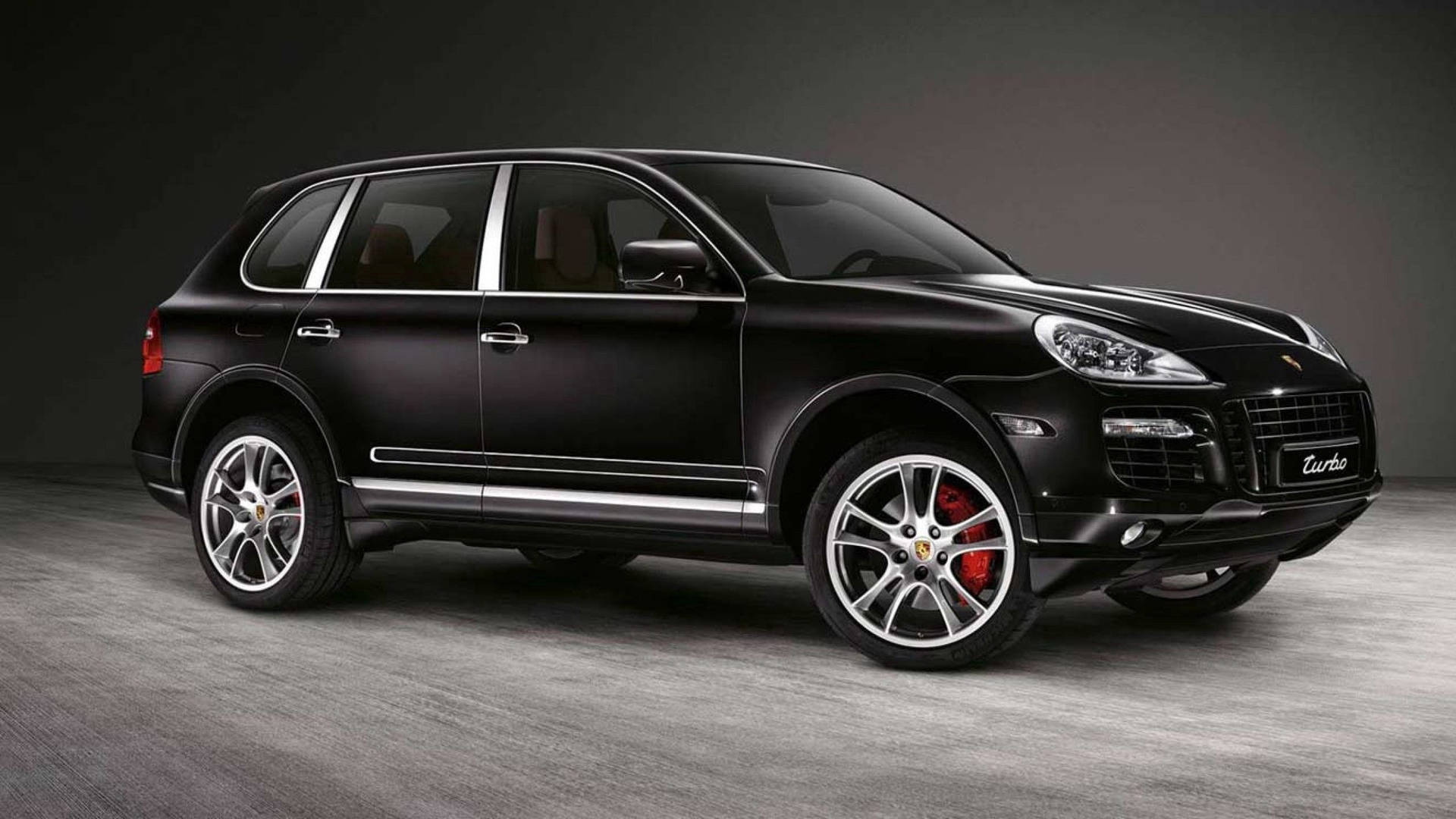 啞光黑色保時捷卡宴 Turbo SUV，紅色制動器，銀色飾條，攝影棚。